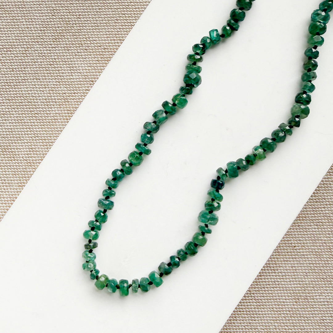 Green kyanite gemstone necklace on a white card with a neutral background