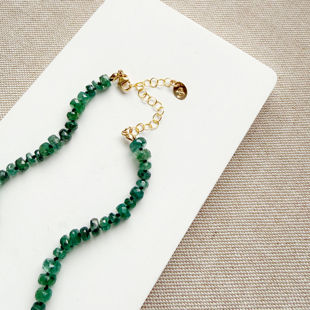 Clasp detail of a green kyanite gemstone necklace on a white plate with a neutral background