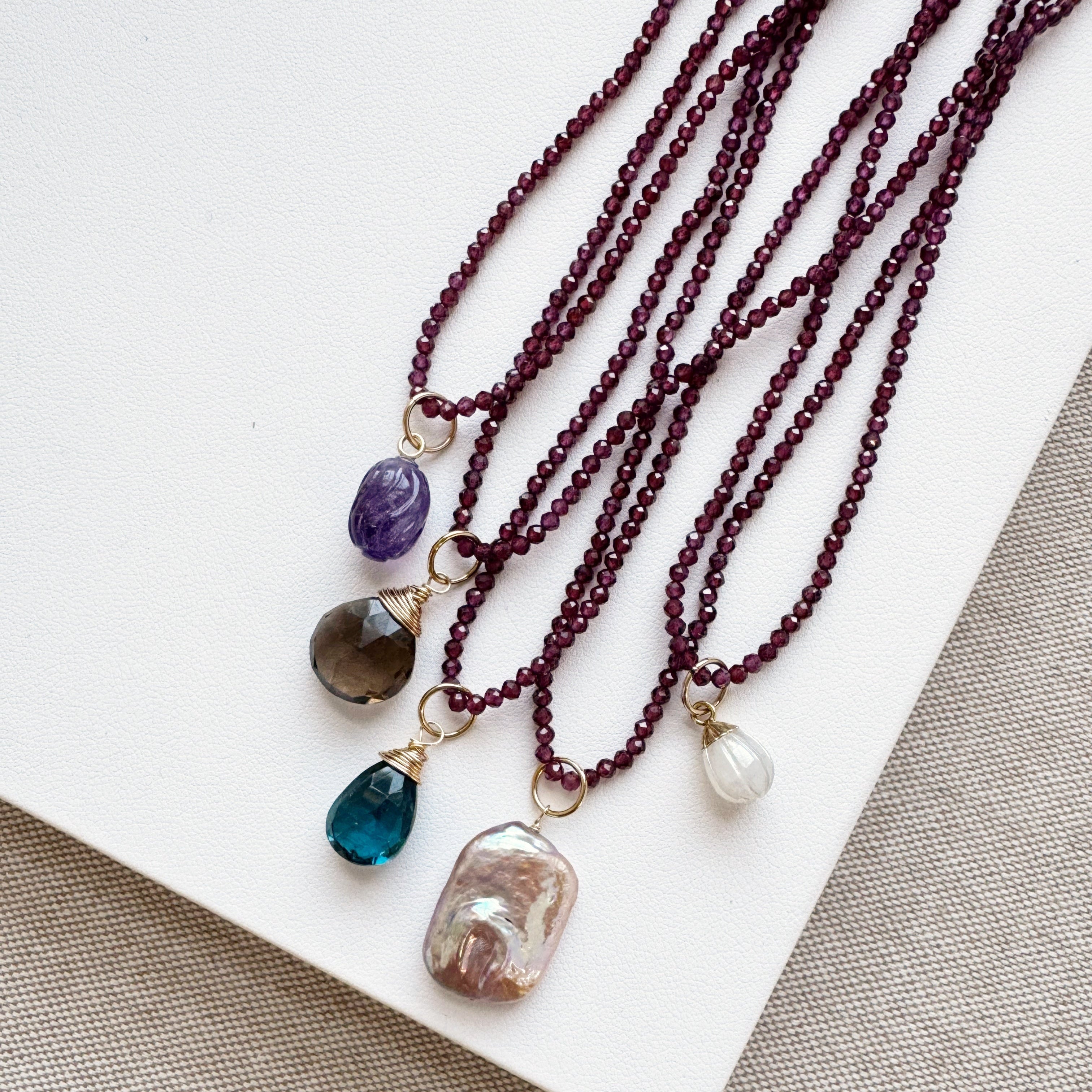 Three beaded necklaces with various colored stones on a white surface.