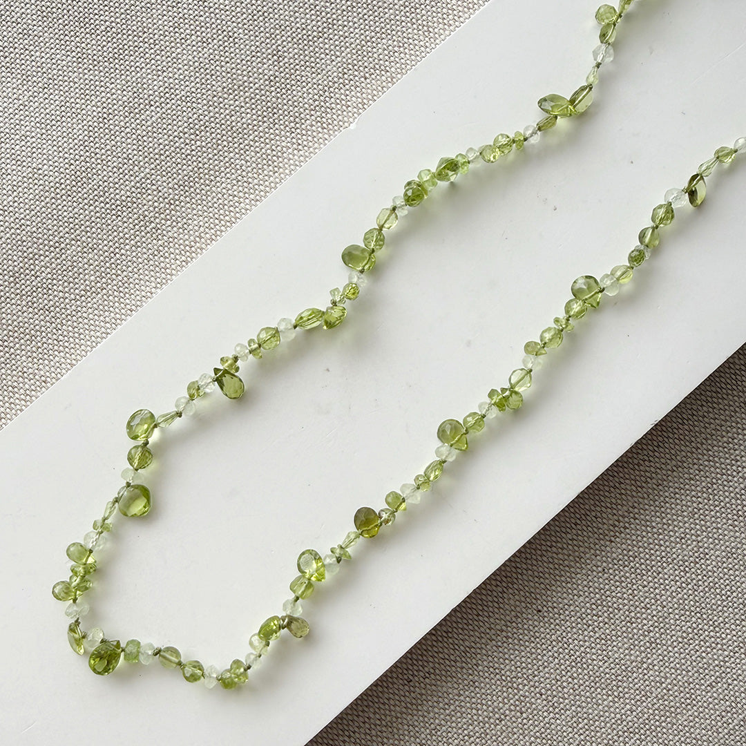 Gemstone necklace in shades of green on a white surface