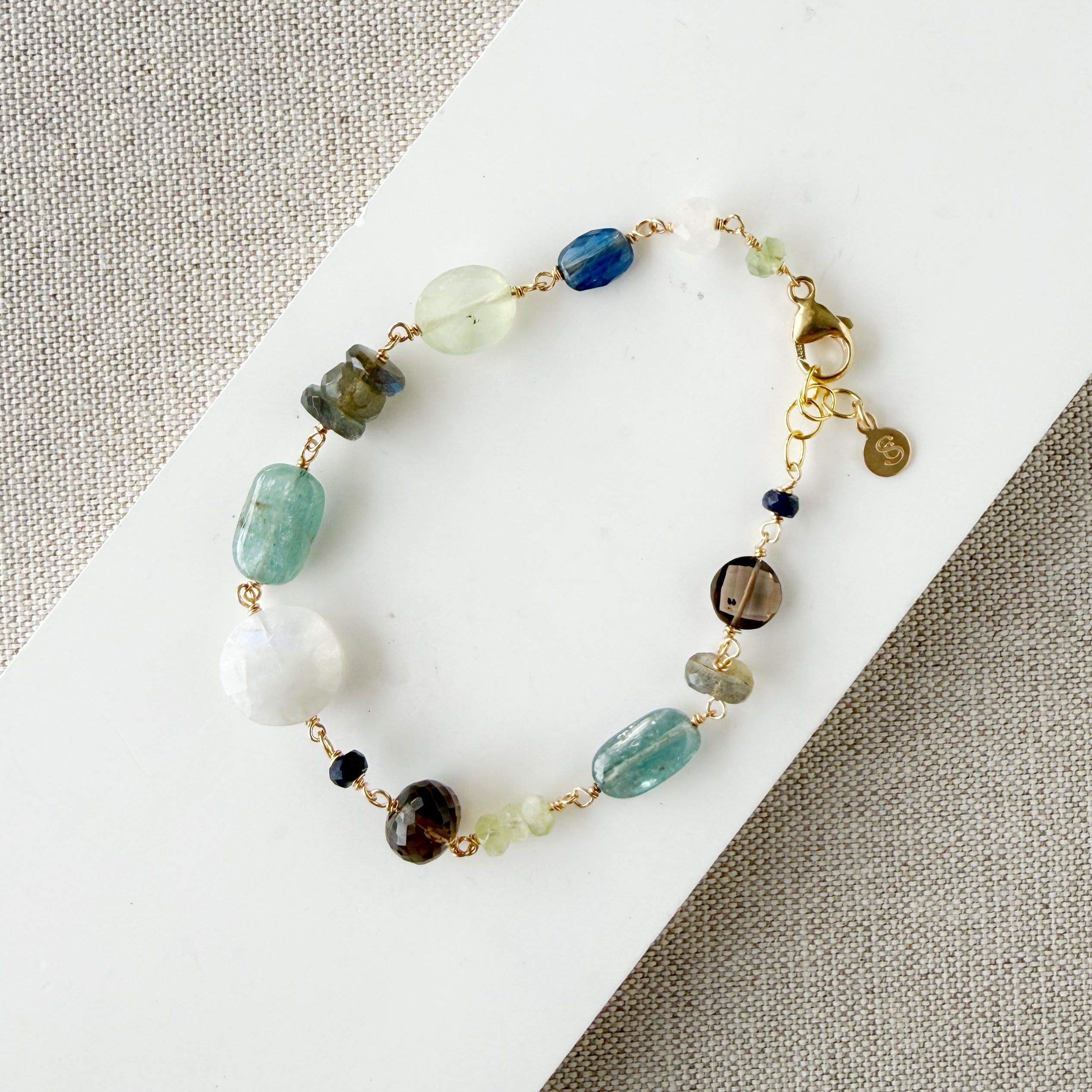 Multicolored chunky gemstone bracelet on a white square card with a textured beige background