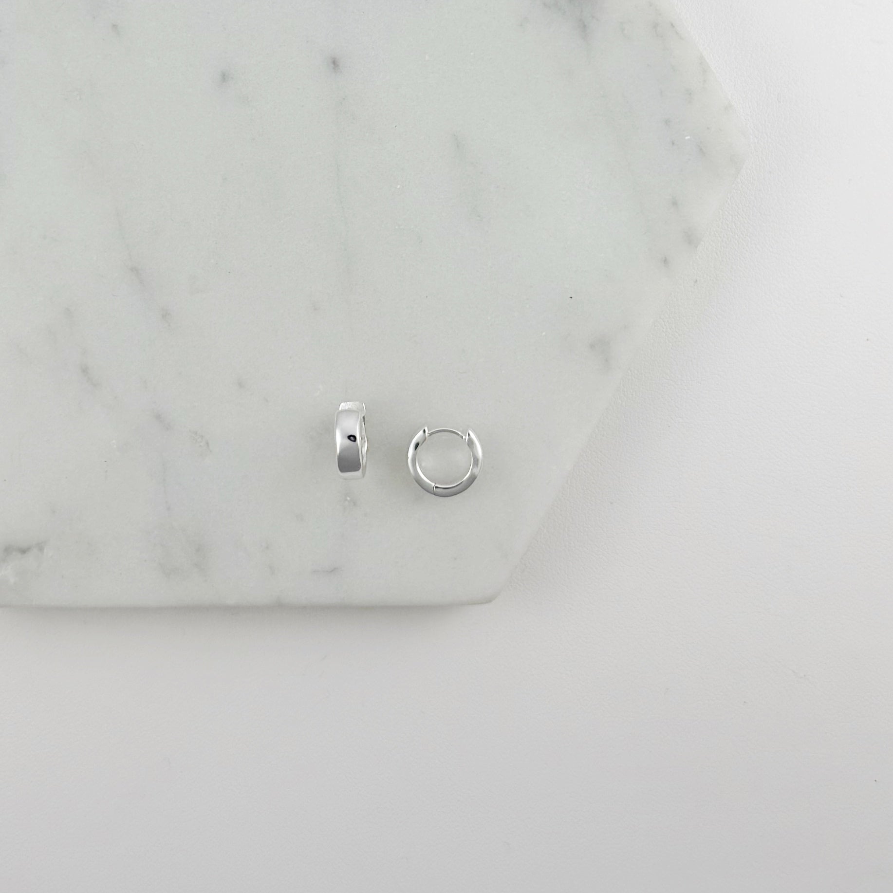 Two silver hoop earrings on a marble surface