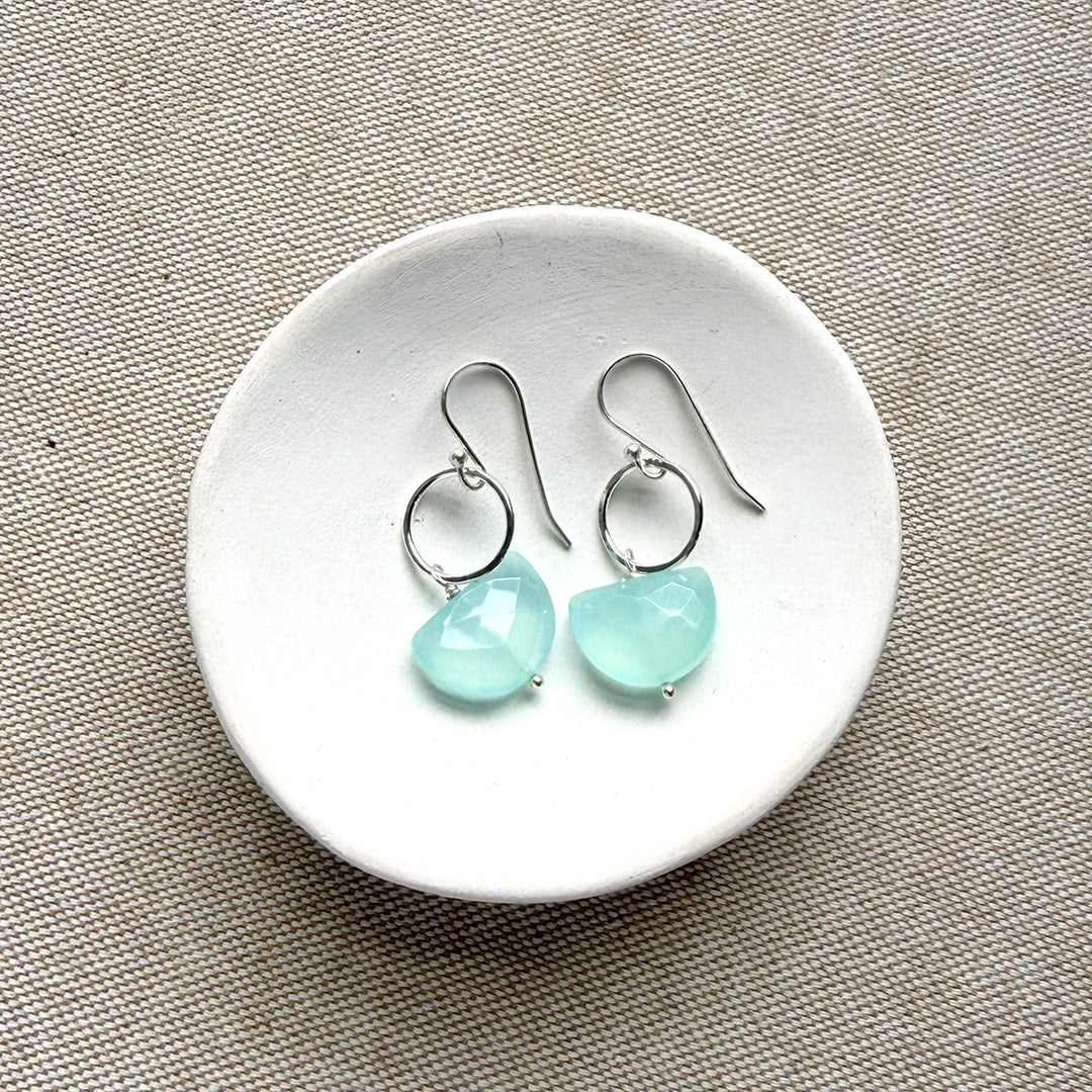 Pair of earrings with blue chalcedony stones on a white dish.