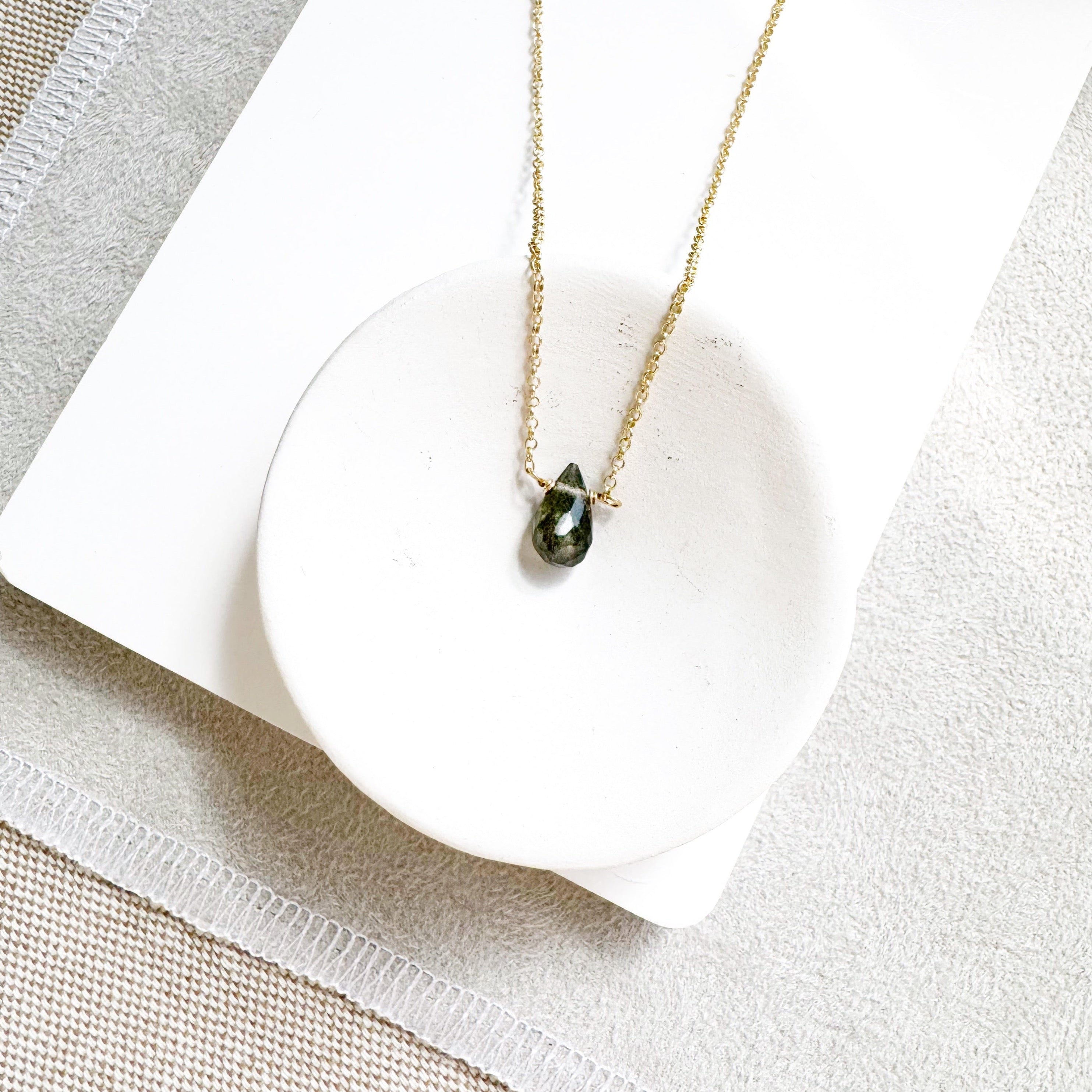 Labradorite One Love necklace with different gemstones in a white dish