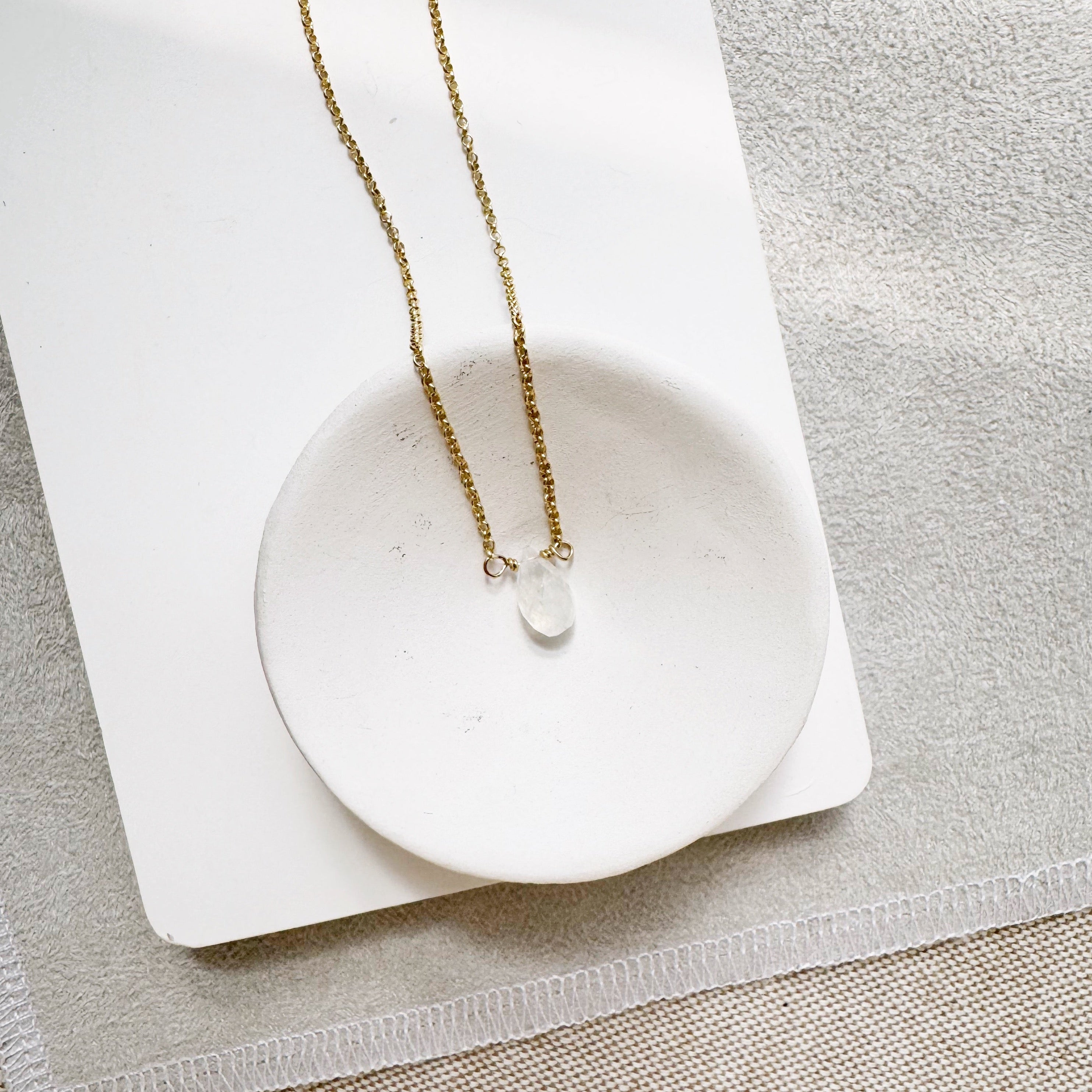 White One Love necklace with different gemstones in a white dish