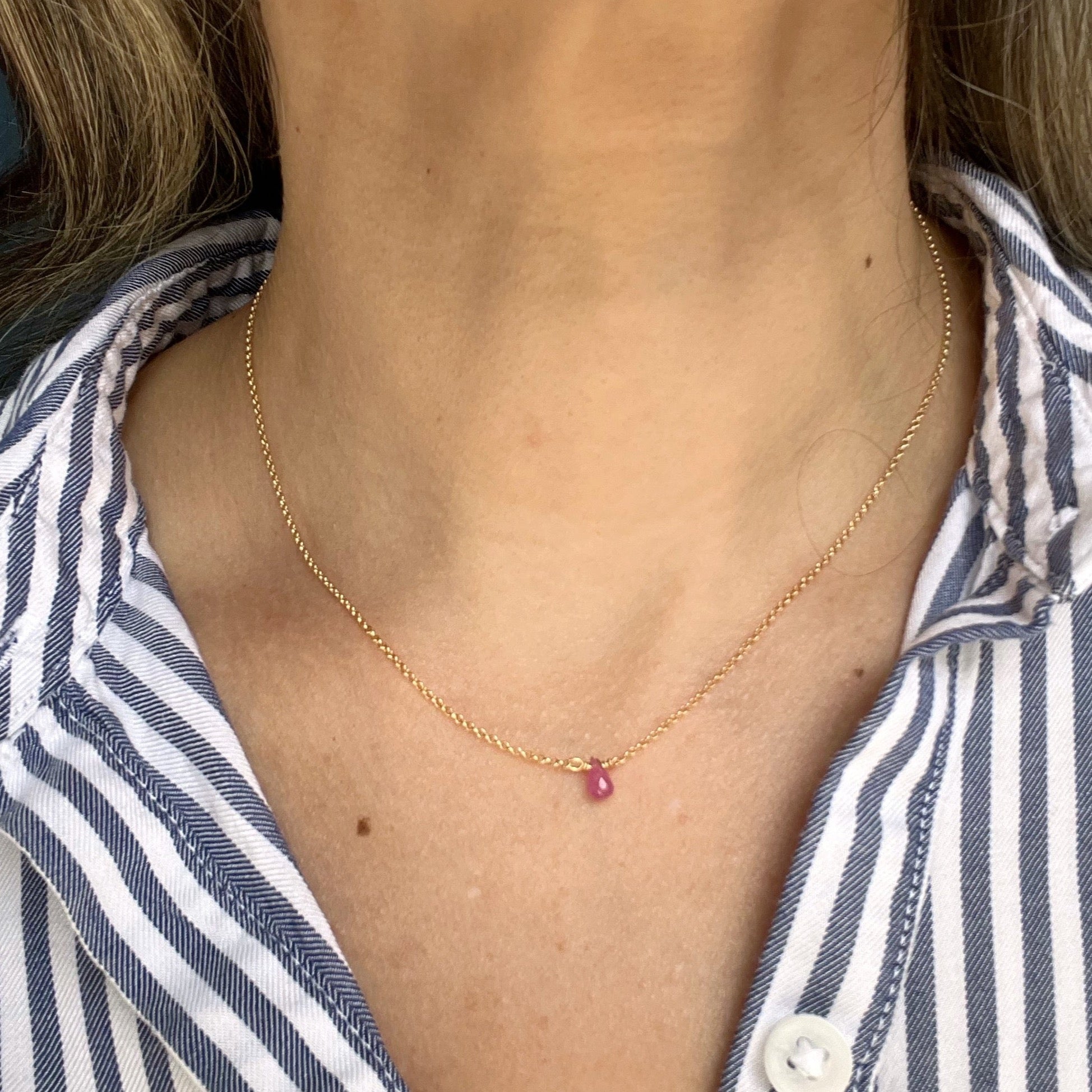 Close up of woman wearing pink one love necklace