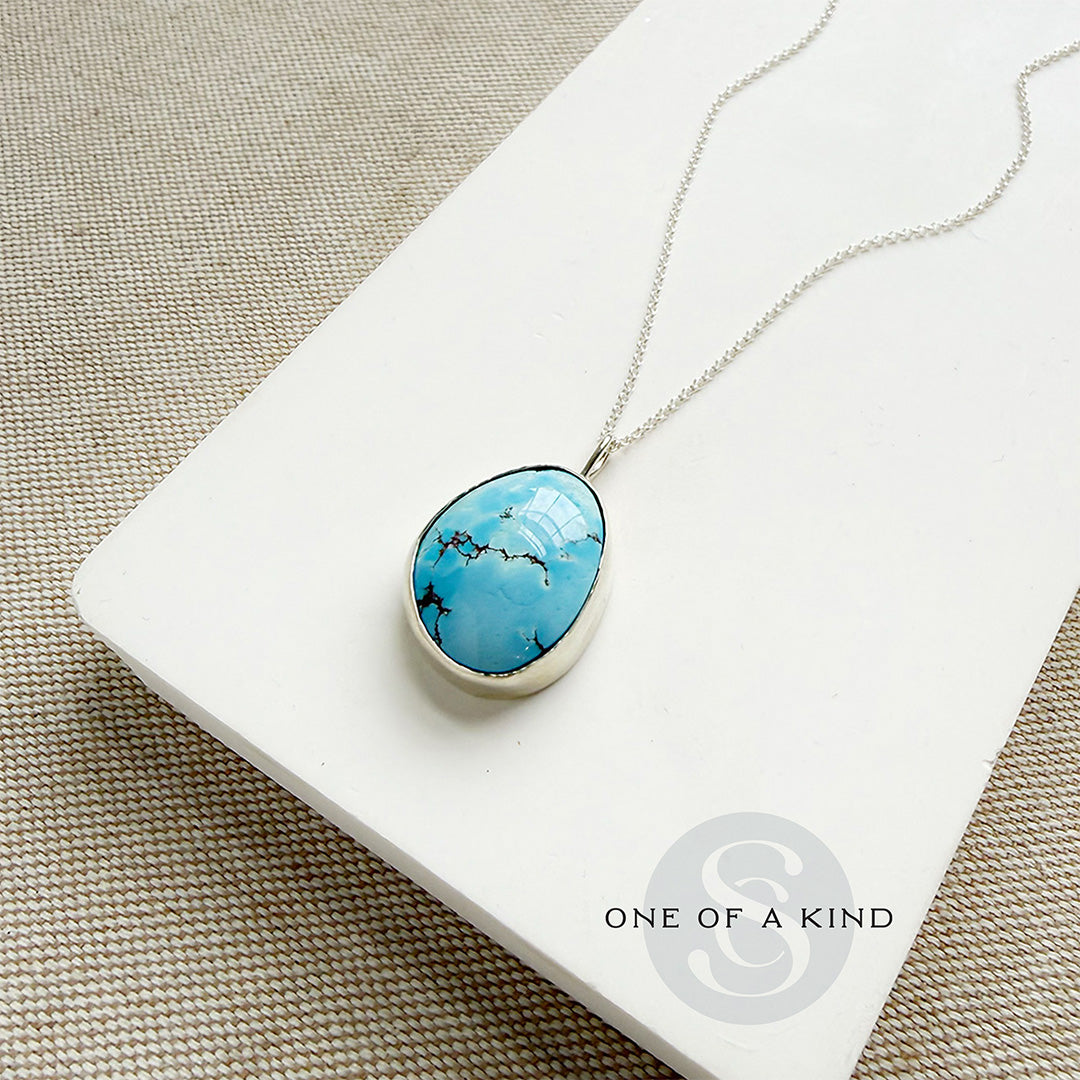 Golden Hills turquoise pendant necklace in sterling silver on a white card with 'One of a Kind' branding.