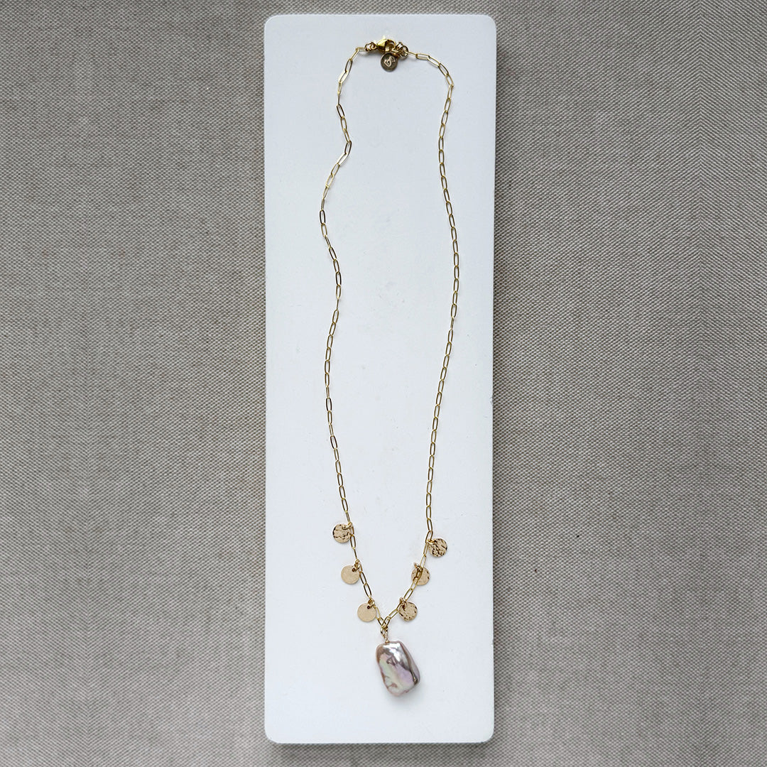 Gold and baroque pearl necklace on a white dish