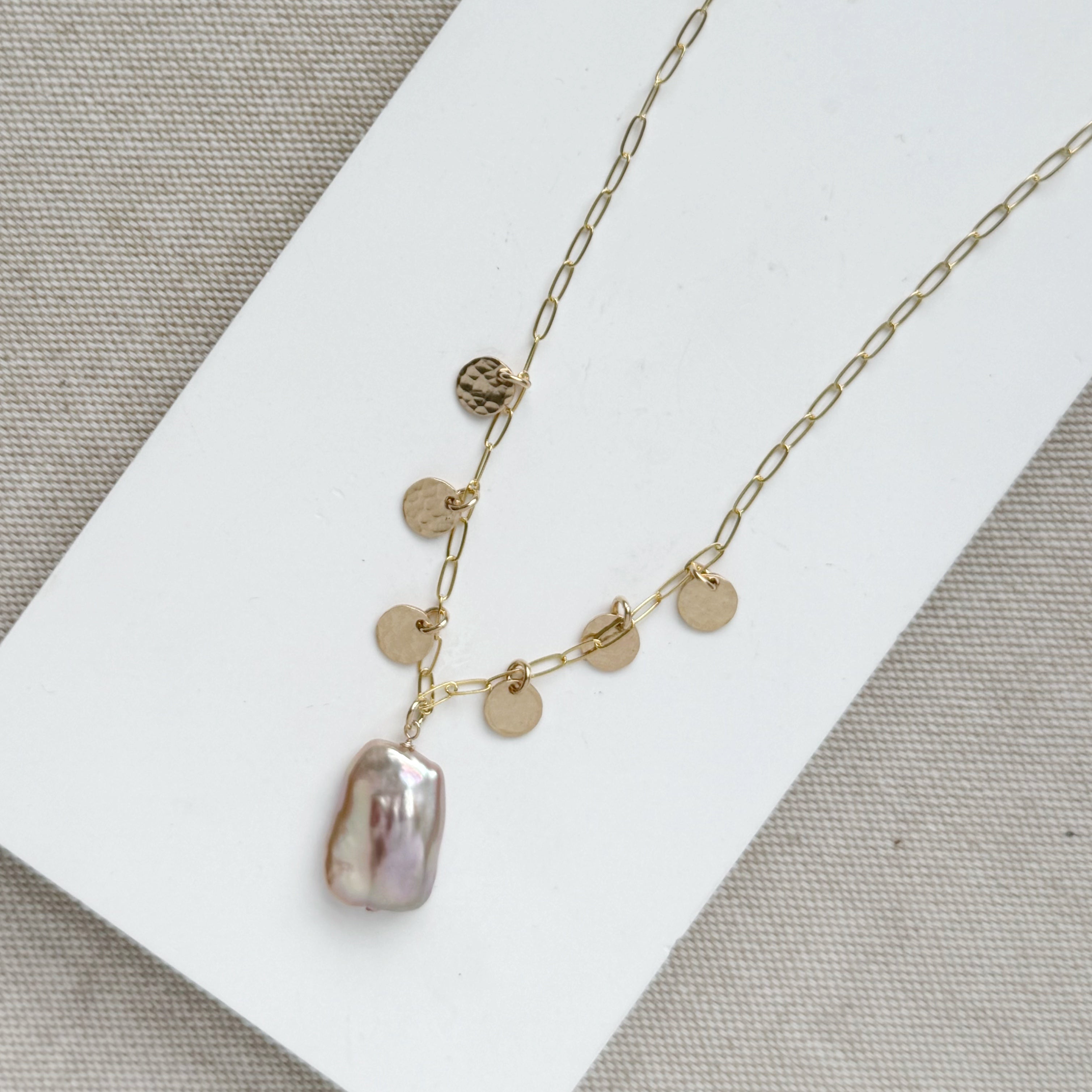 Close up of gold and baroque pearl necklace on a white tray