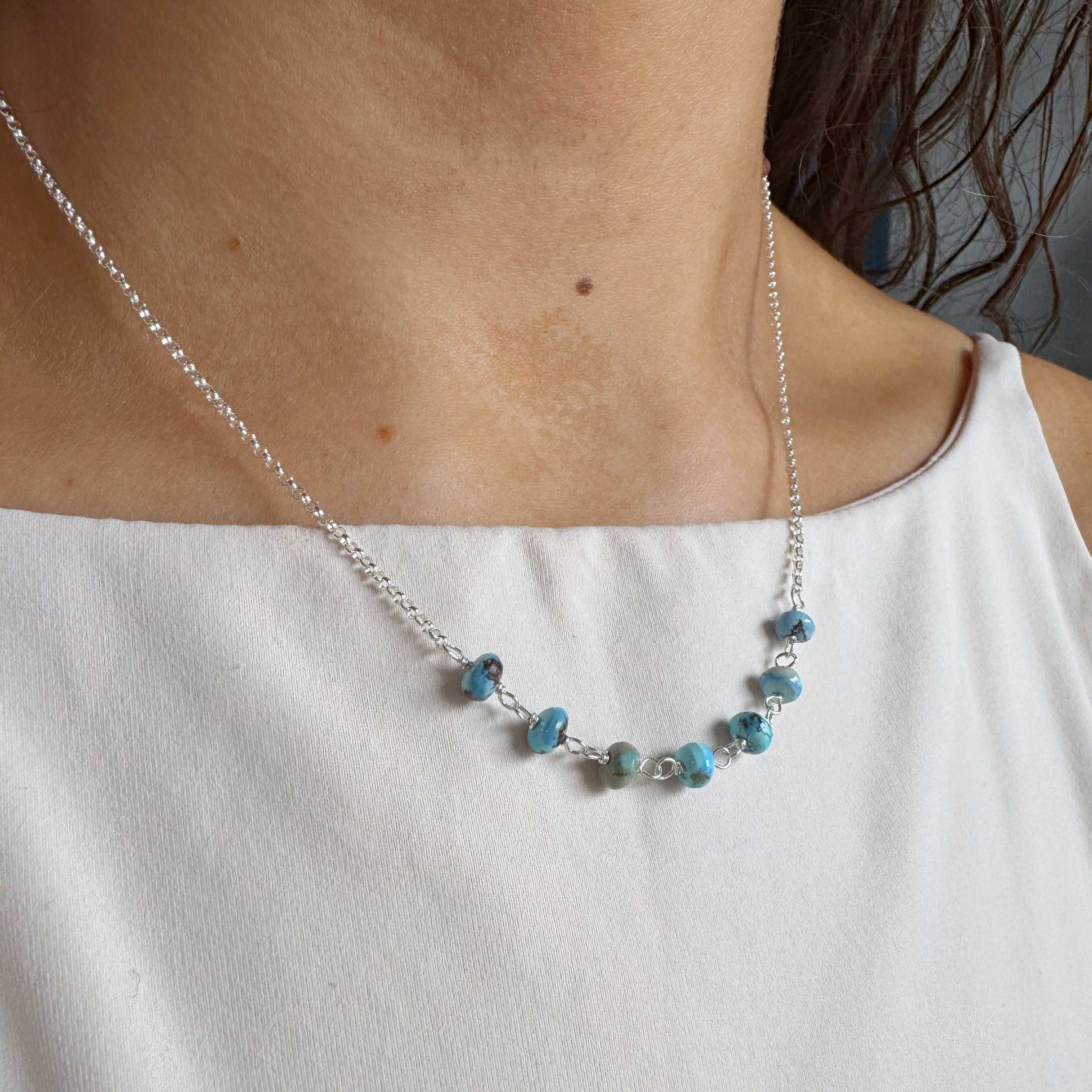 Silver necklace with Golden Hill turquoise beads worn by a person on a white background
