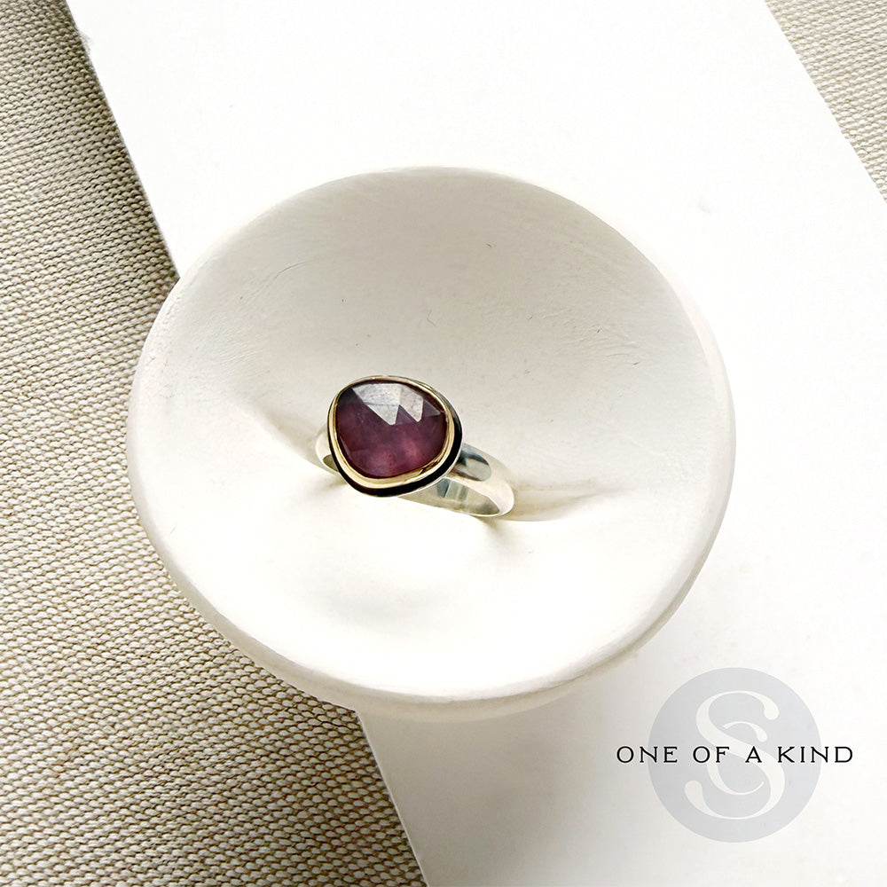 Rose cut pink sapphire mixed metal ring set in a white dish