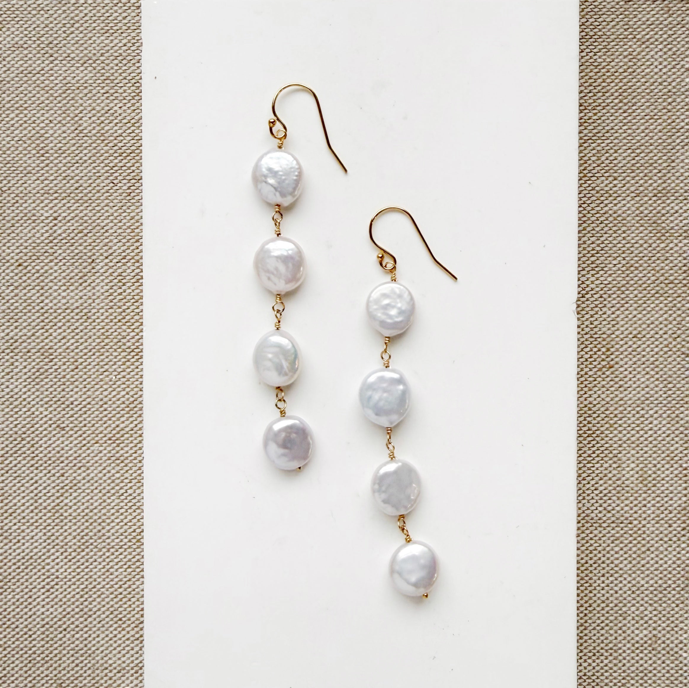 White coin pearl statement earrings on a white card