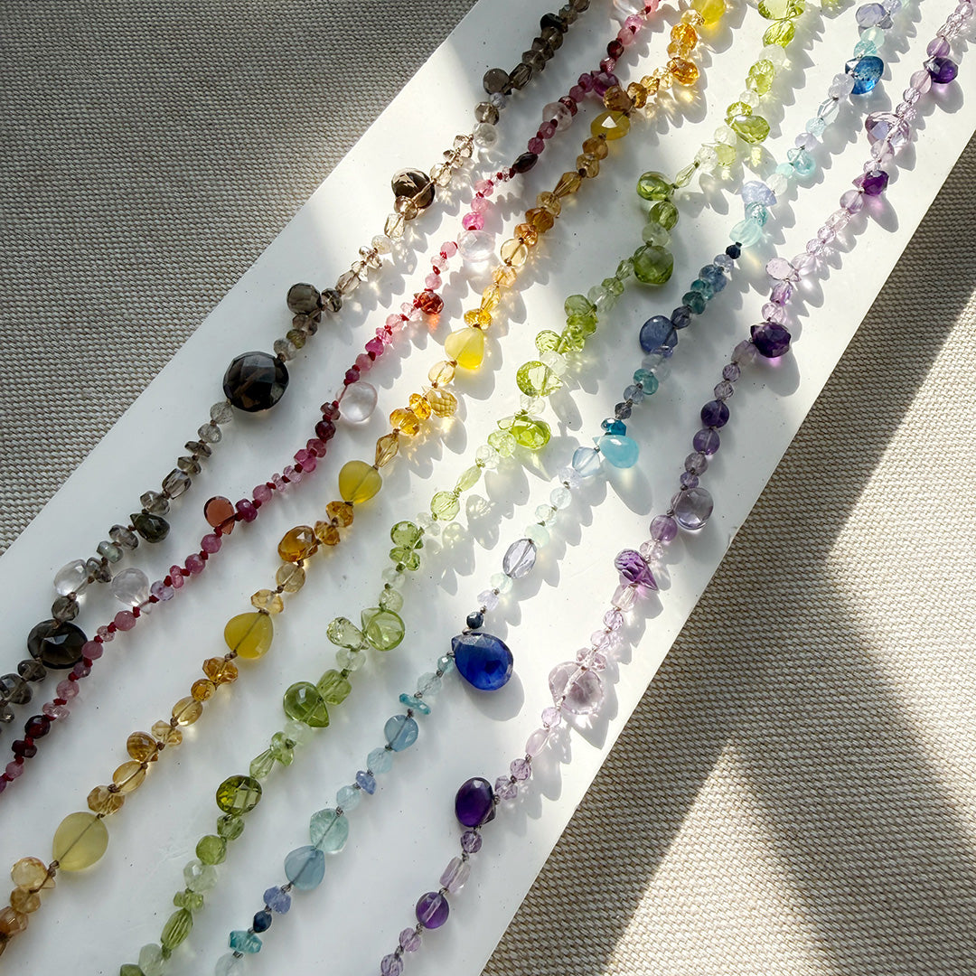 Colorful gemstone necklaces on a white surface