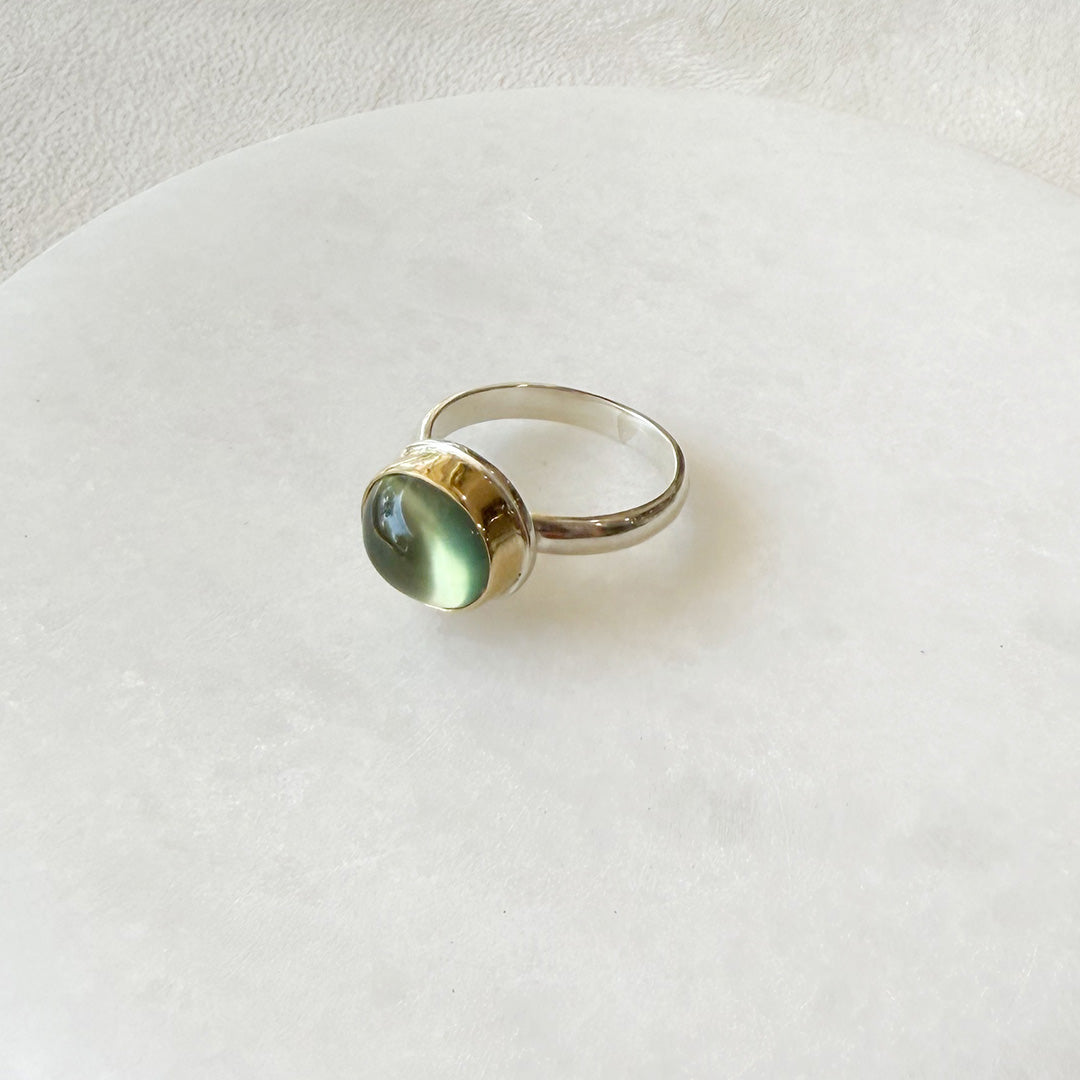 Ring with a green prehnite gemstone on a white plate on a white plate
