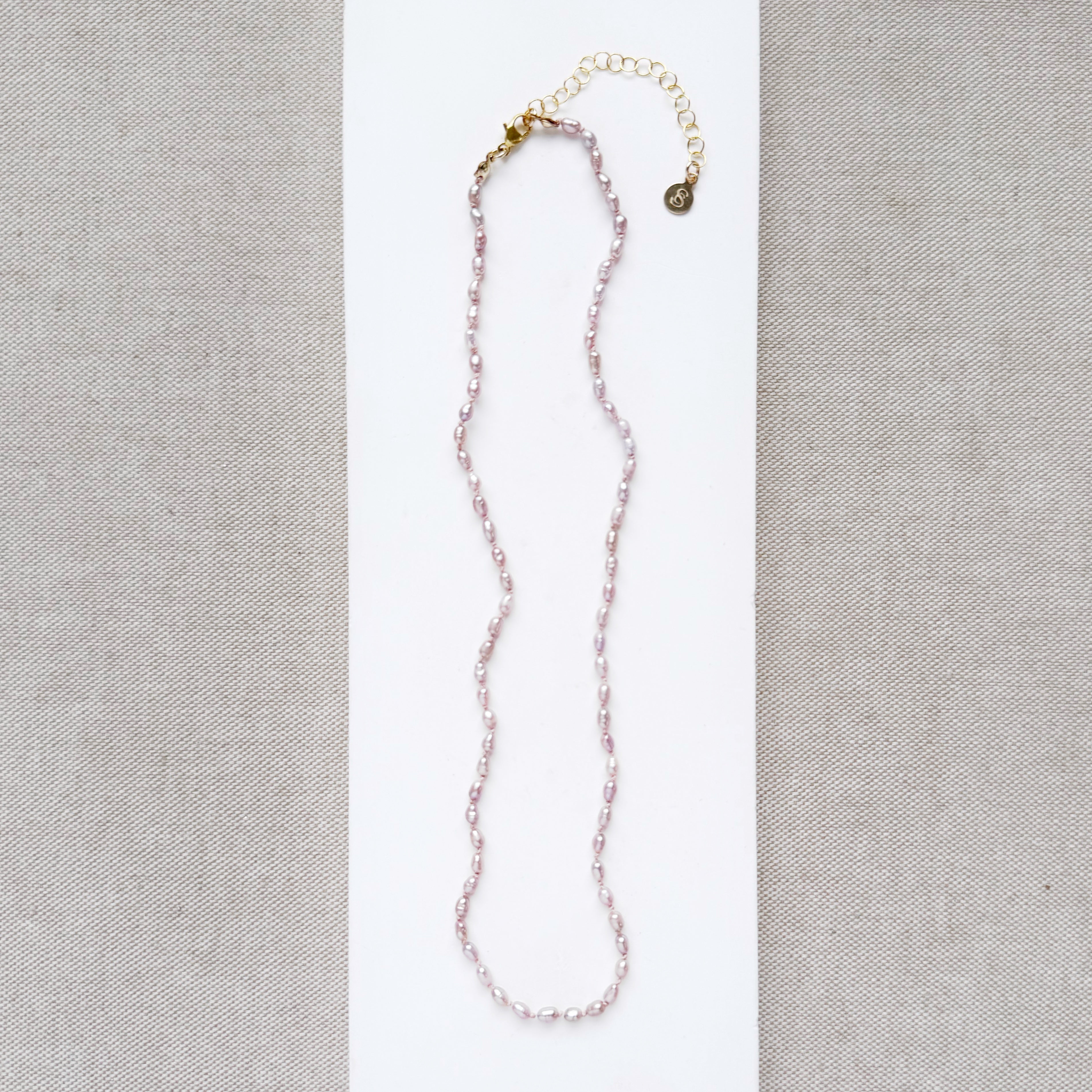 Knotted necklace with tiny pink pearls on a white card