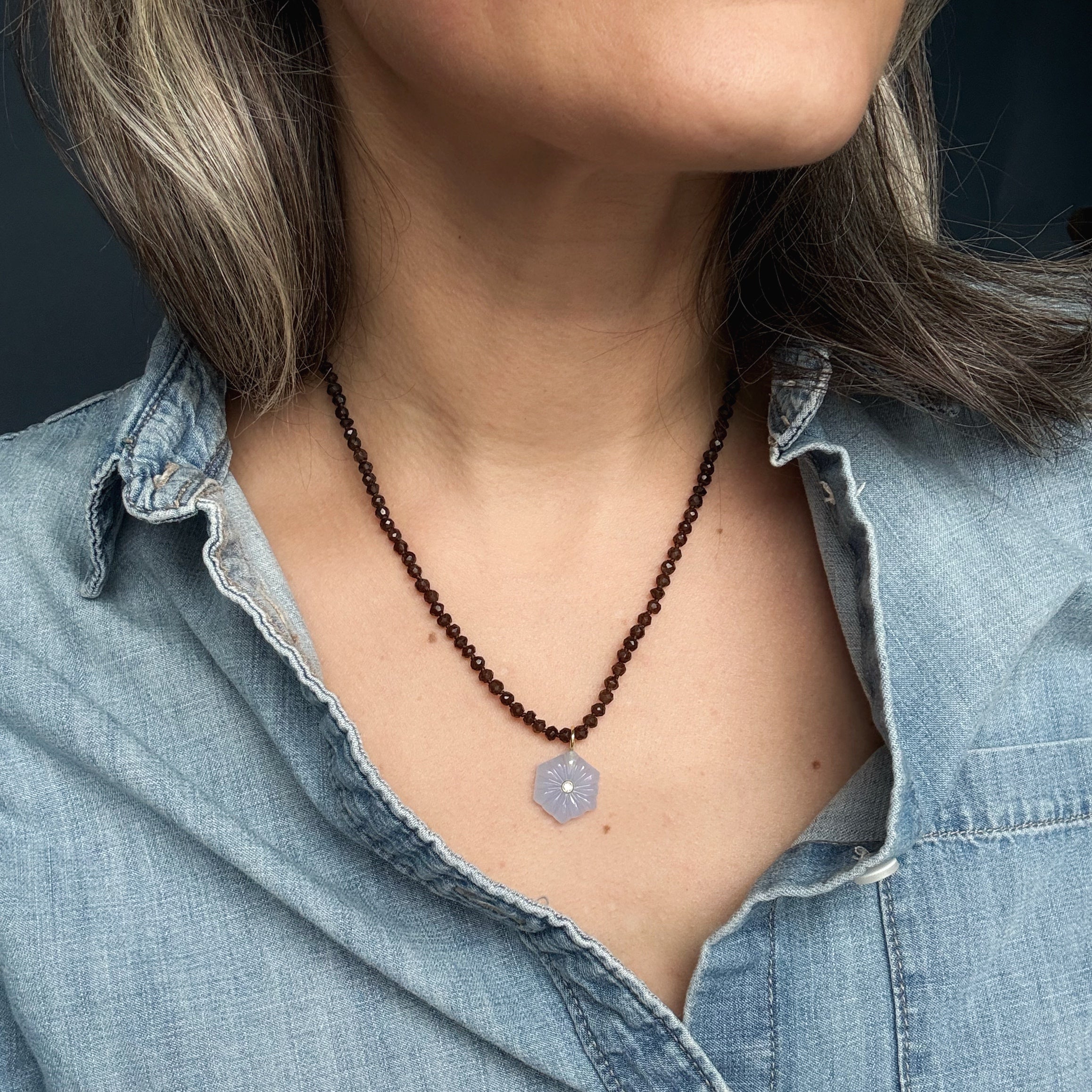 Close up of woman wearing gemstone necklace with carved pendant