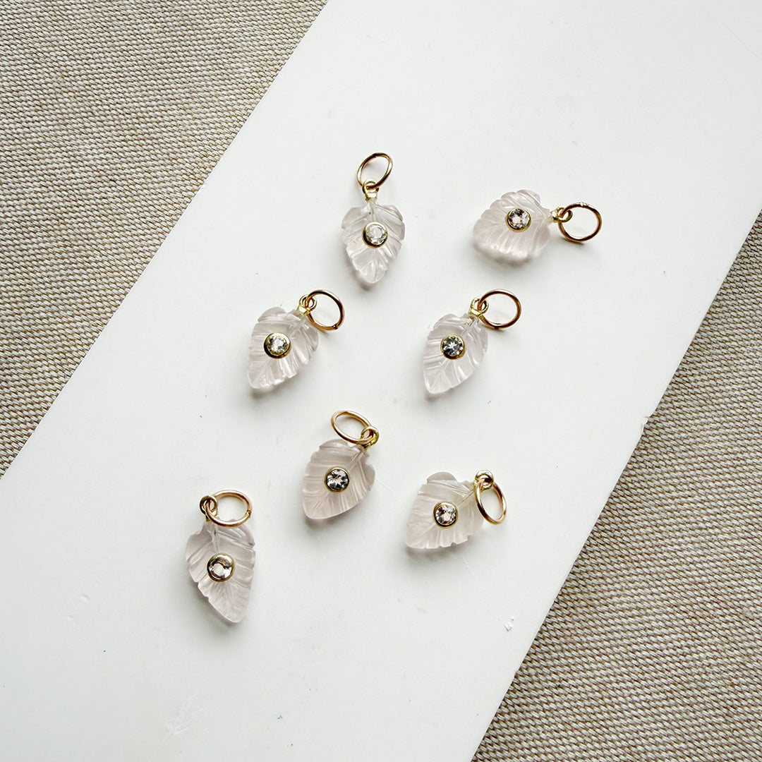 Carved leaf charms in rose quartz on a white plate