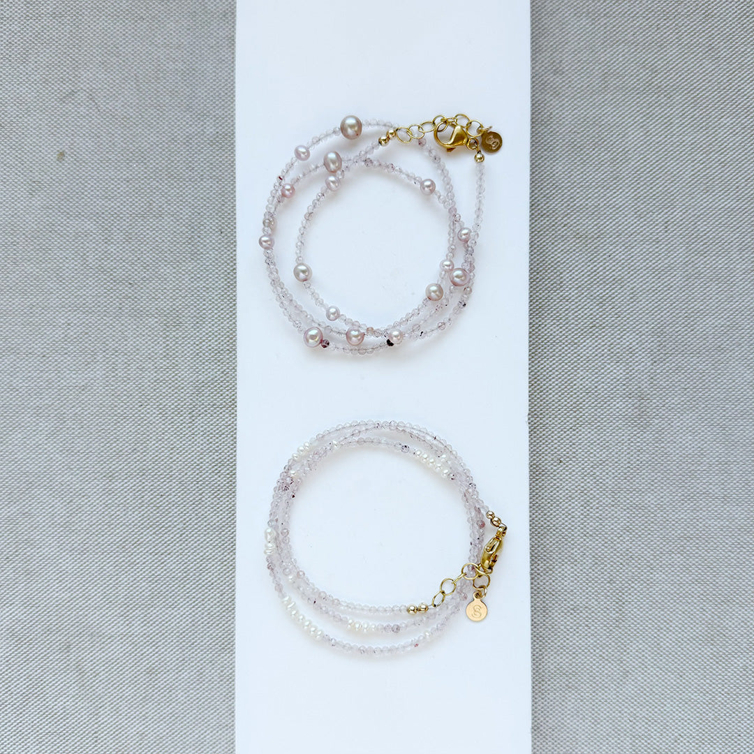 Two pearl and rose quartz bracelets with gold clasps on a white background