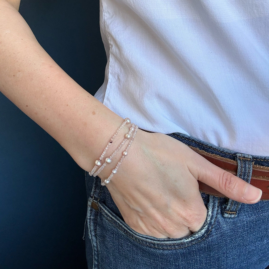 Person wearing a white shirt and blue jeans with option 2 bracelet on a dark background