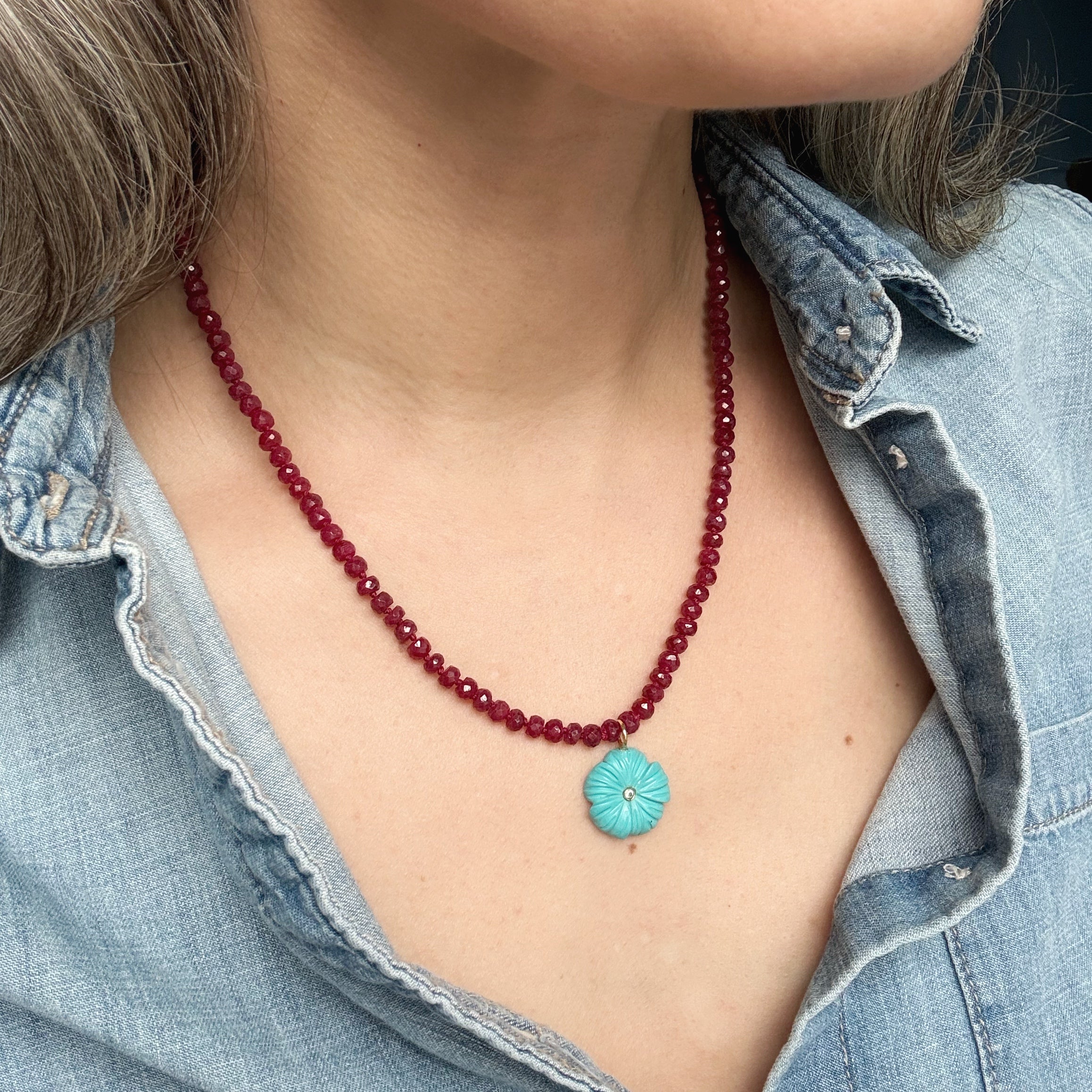 Close up of woman wearing gemstone necklace with carved pendant