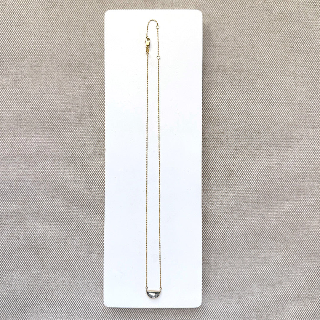 Solid gold necklace with a half moon salt and pepper diamond pendant on a white card.