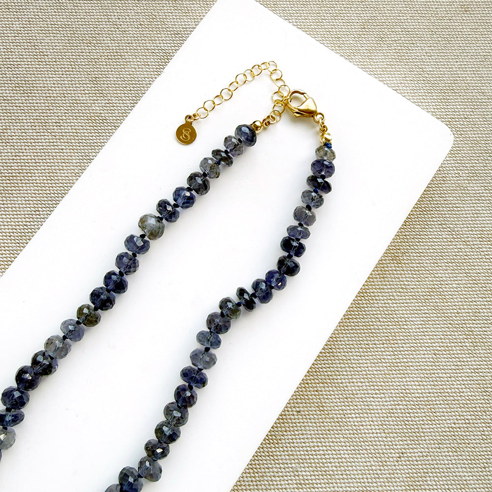 Clasp detail of a knotted iolite gemstone necklace with gray baroque pearl
