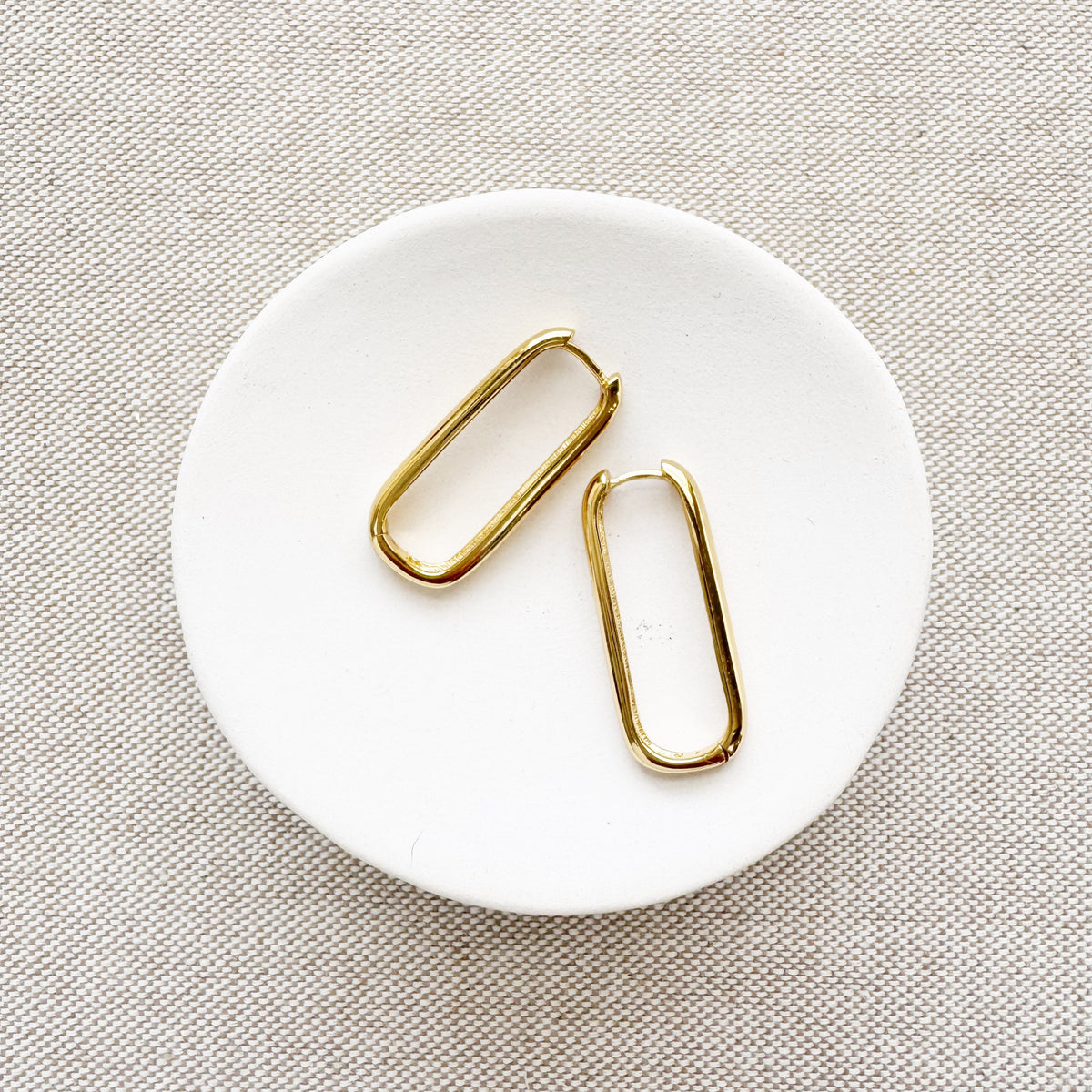 A pair of gold vermeil hoop earrings placed on a white plate.