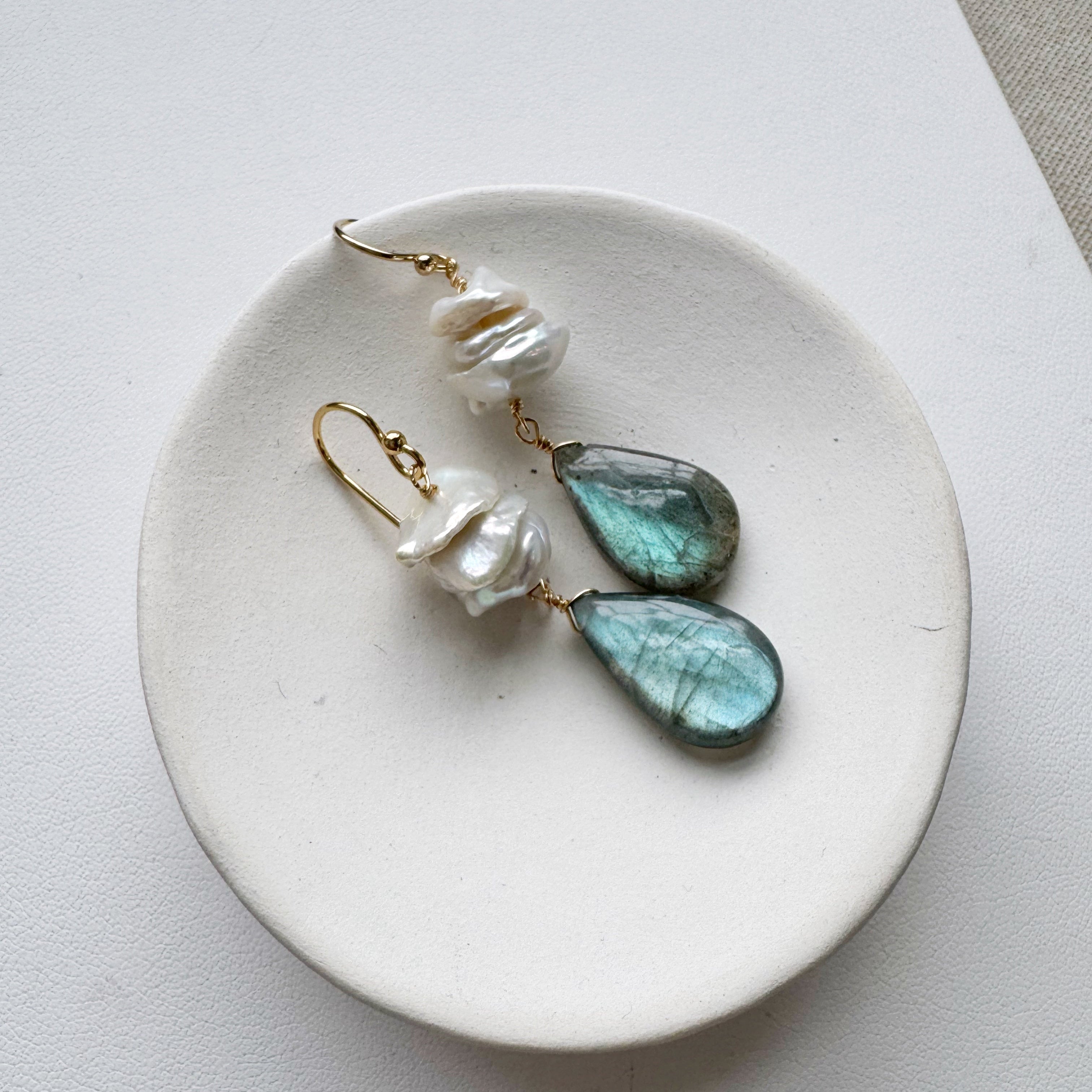 Statement earrings with pearl and labradorite in a small white dish