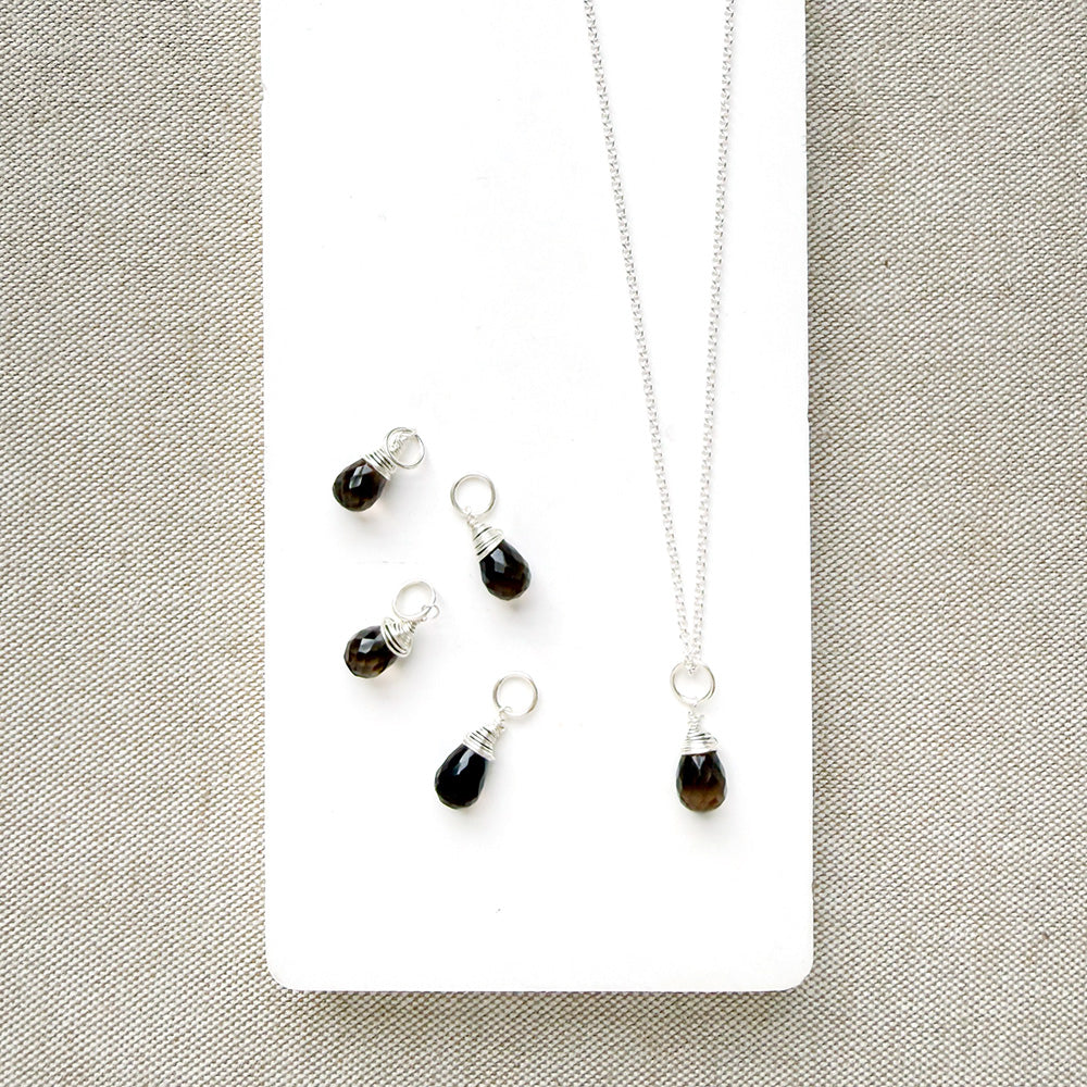Smokey Quartz charm on a silver chain in a white dish
