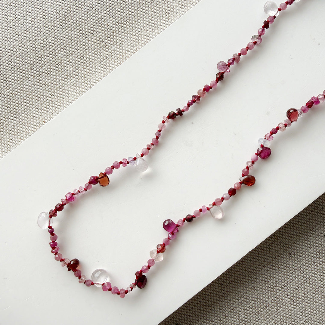 Gemstone necklace in shades of red on a white surface