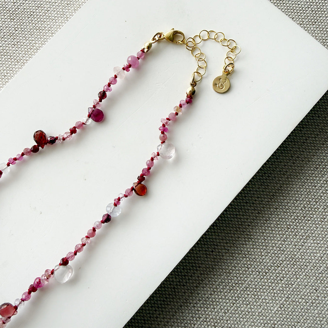 Gemstone necklace in shades of red on a white surface