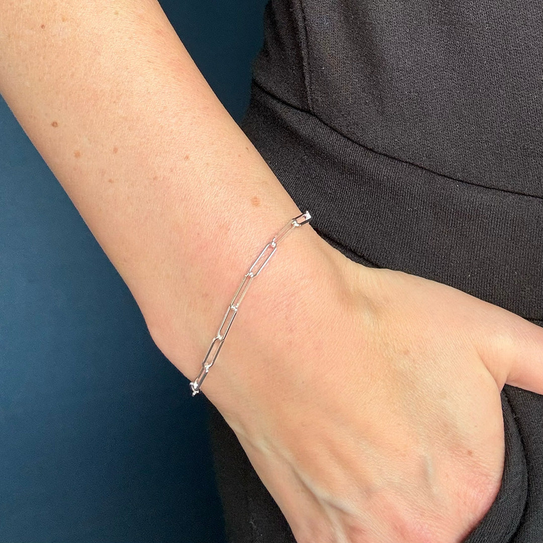 Silver bracelet on a person's wrist against a dark background