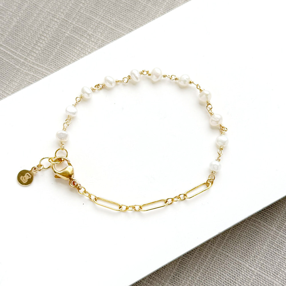 Pearl and chain bracelet on a white plate
