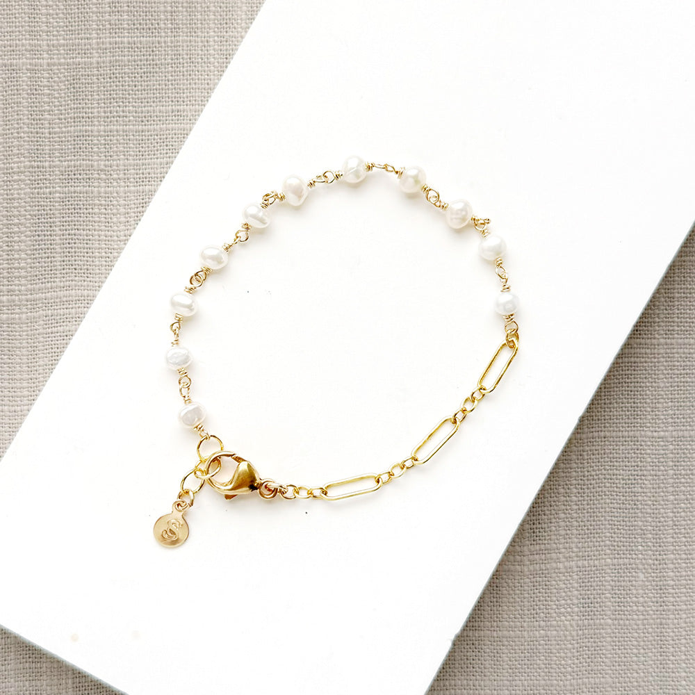 Pearl and chain bracelet on a white plate