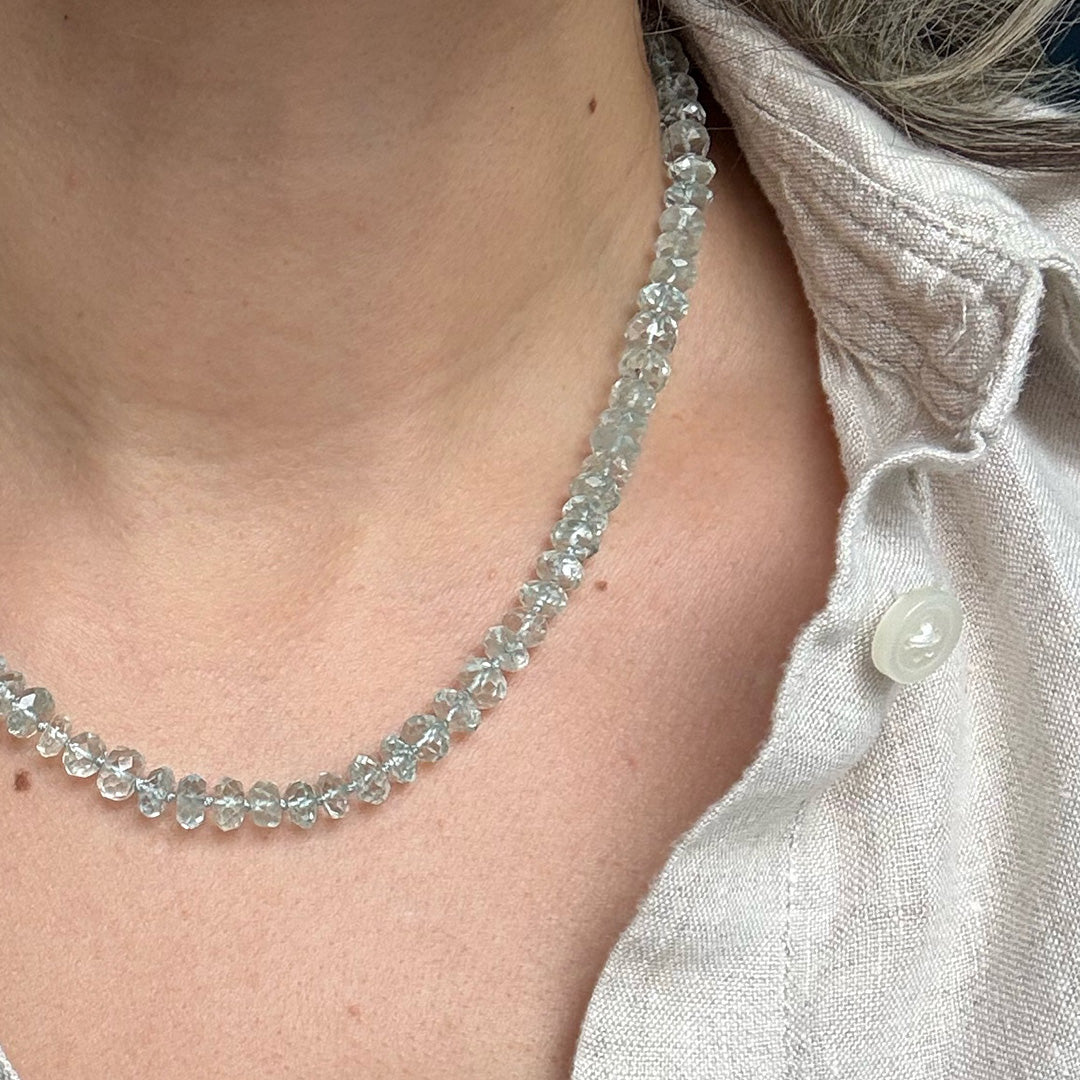 Close up of woman wearing blue topaz necklace on a dark blue background
