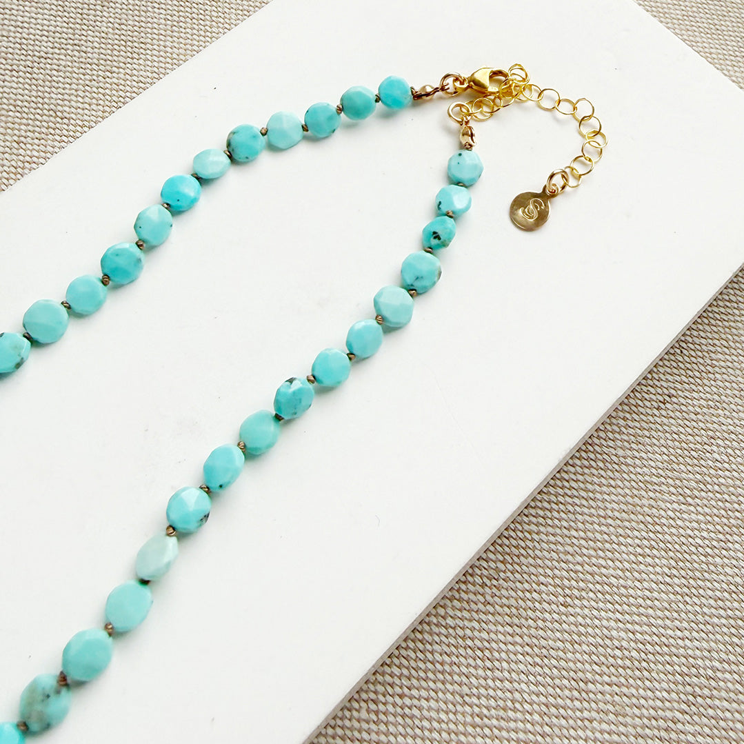 Turquoise beaded necklace with gold clasp on a white card