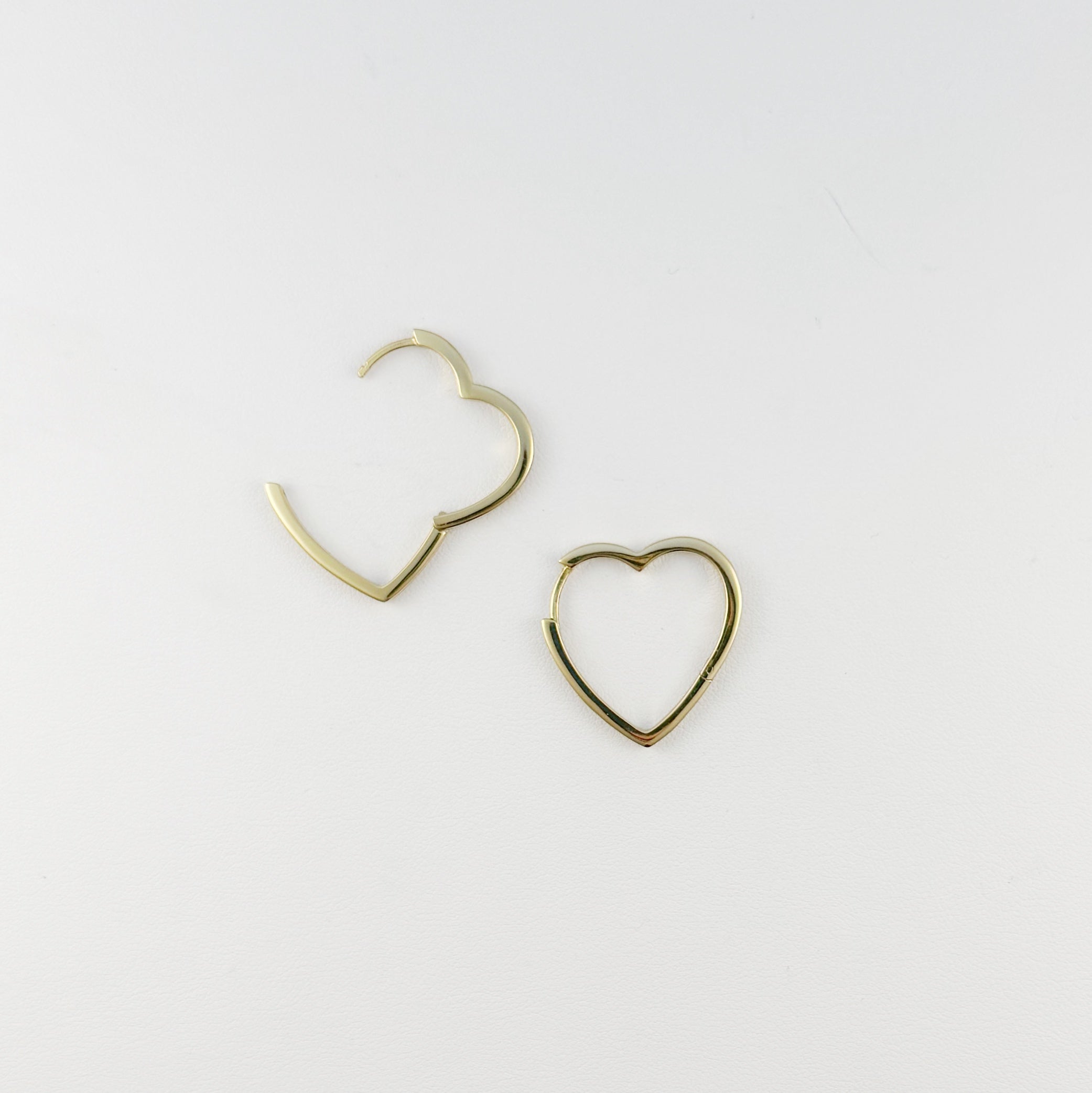 Gold heart-shaped hoop earrings on a light gray background