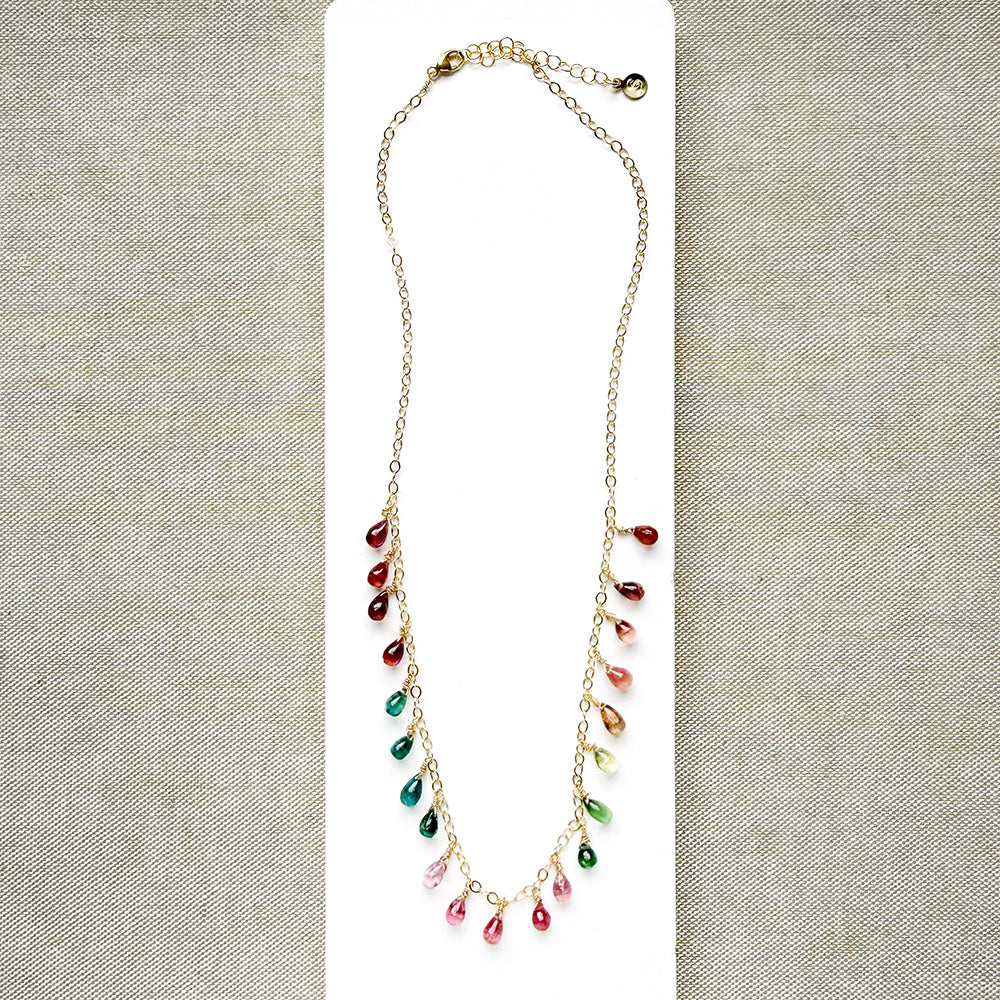 Gold necklace with dangling teardrop-shaped Watermelon Tourmaline gemstones in pink, green, and teal on a white background