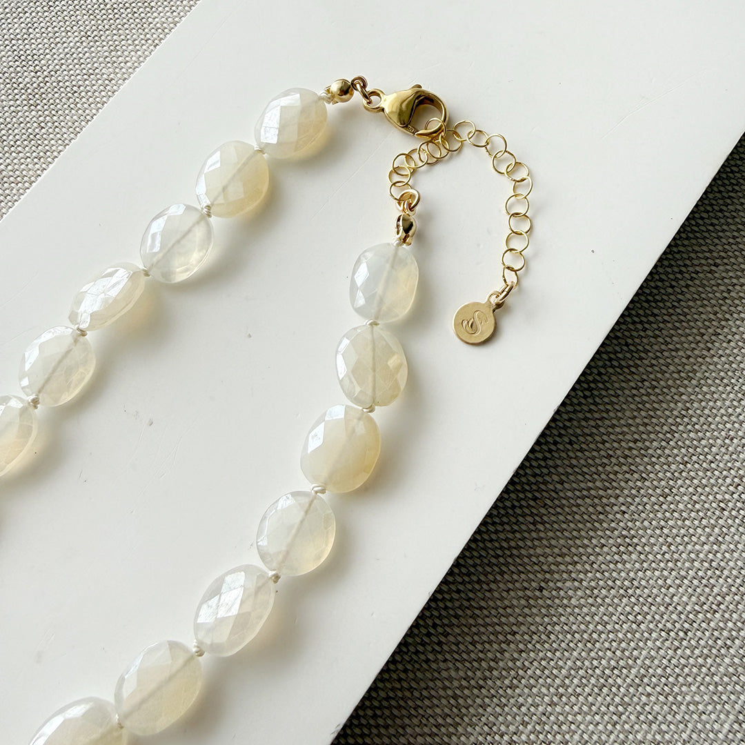 White chalcedony knotted necklace on a white card with a gray background