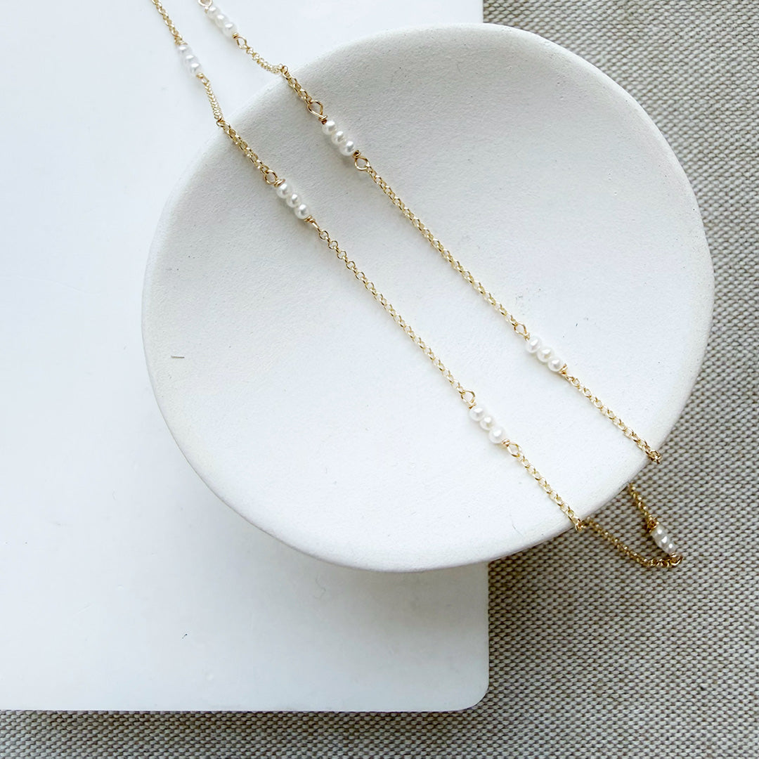 Gold necklace with pearls on a white dish