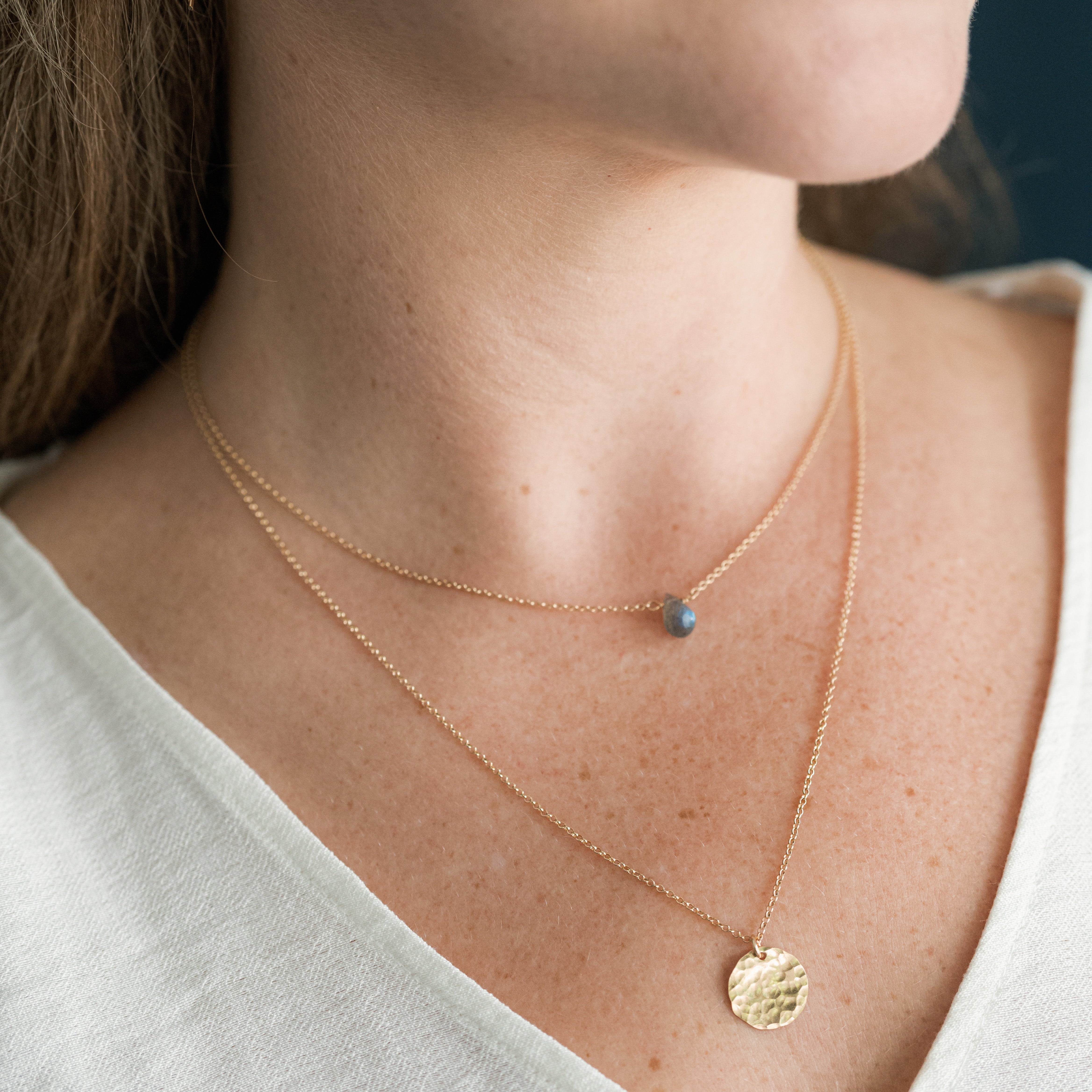Close up of woman wearing two gold necklaces