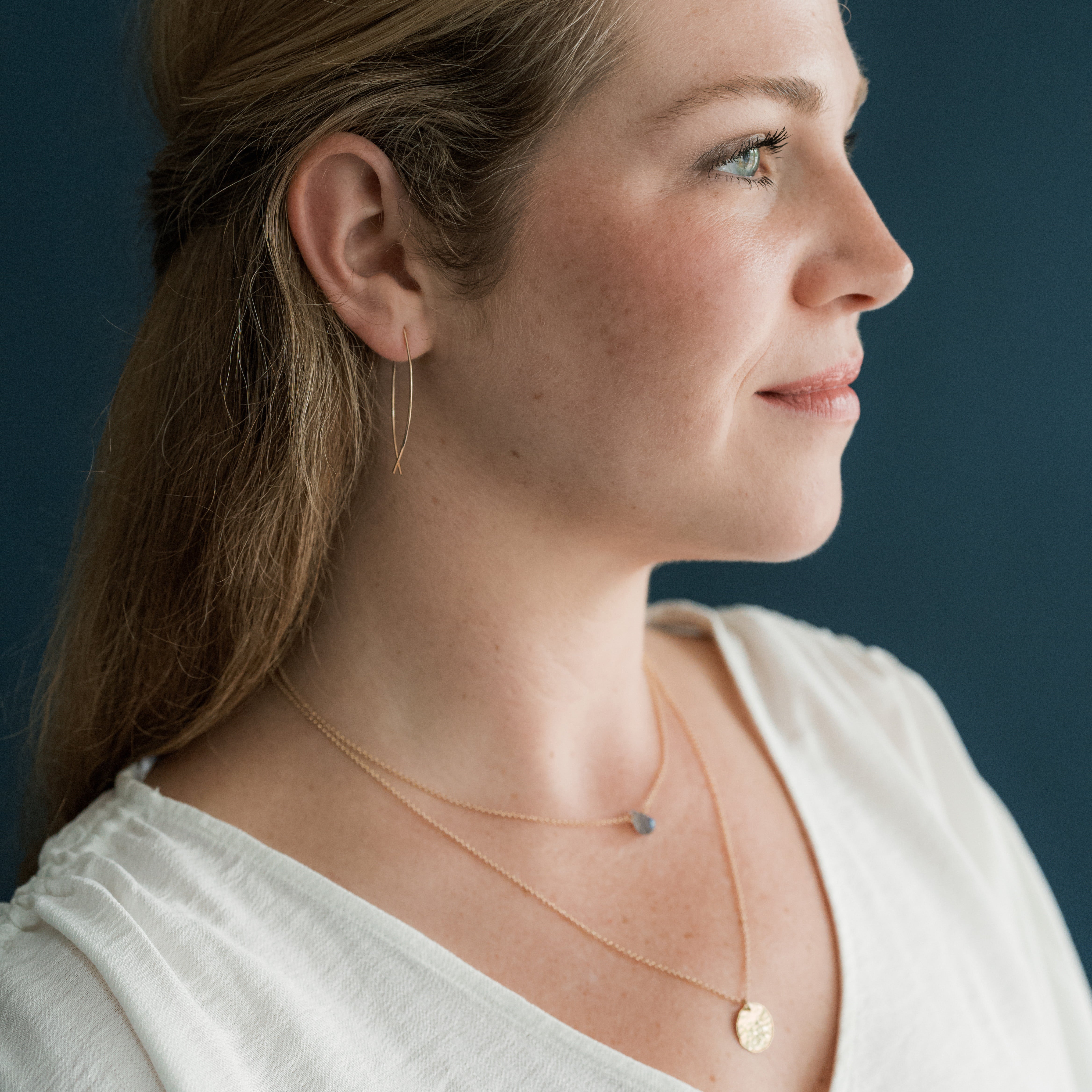 Woman wearing gold necklaces on a dark blue background
