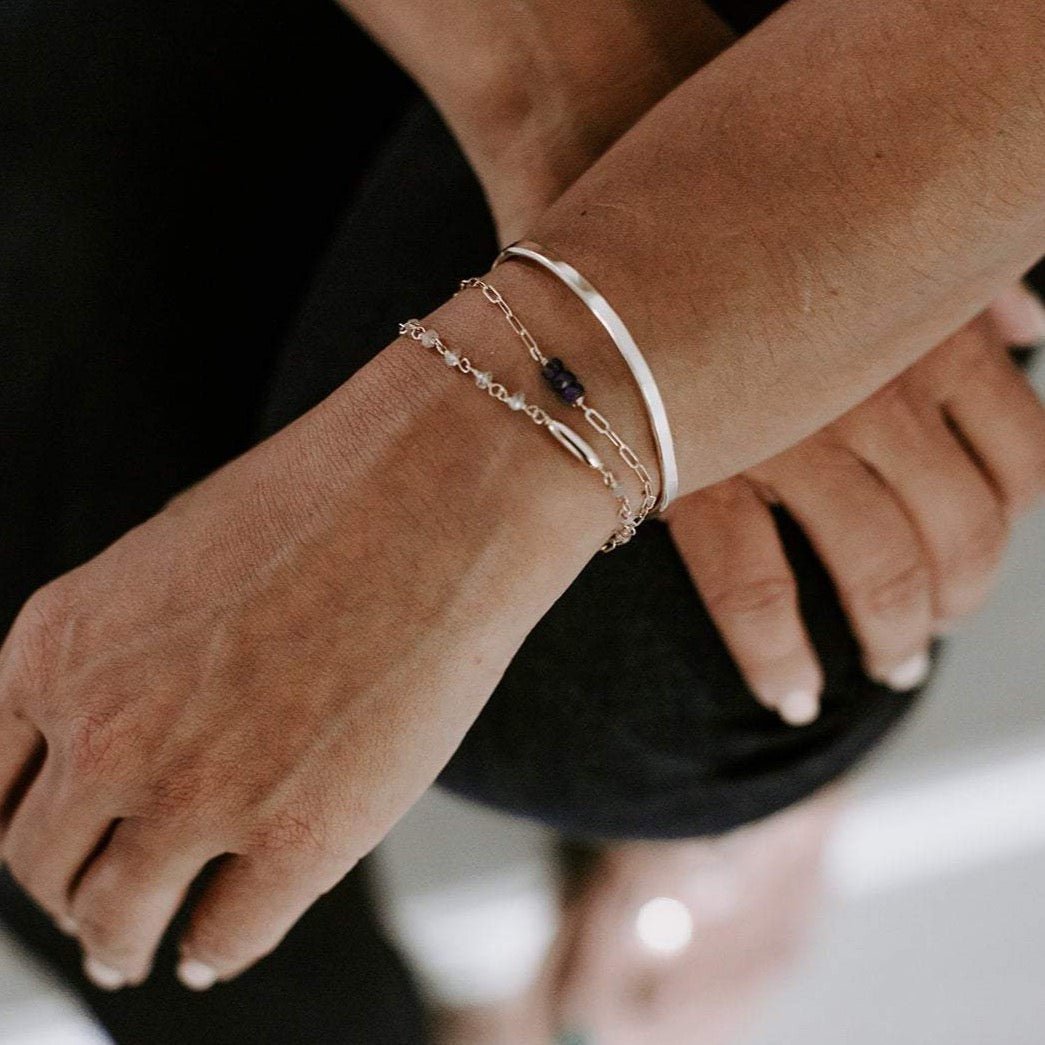 Close up of woman's wrist with silver textured bangle bracelet with the words "always with you" stamped on the inside and 2 silver gemstone bracelets . Always with You Bangle by Sarah Cornwell Jewelry