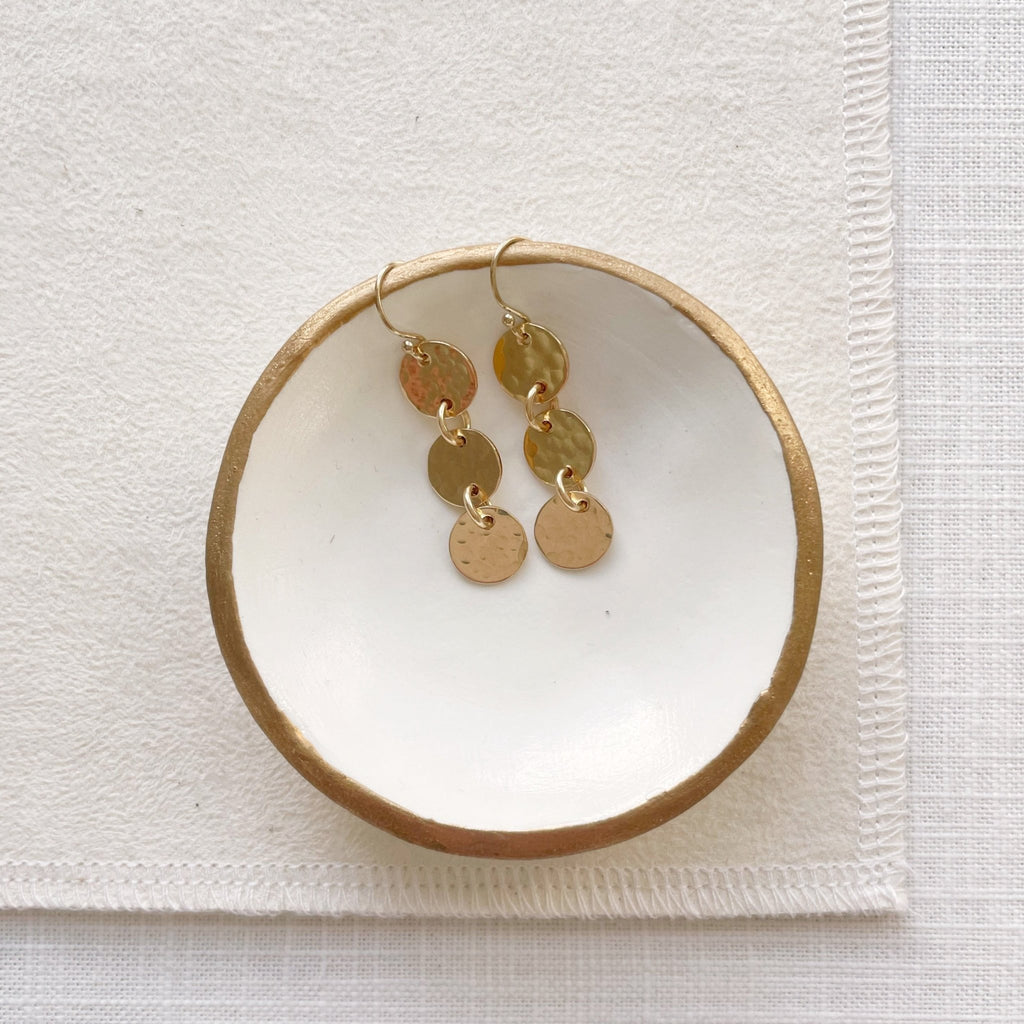 Gold 1.5 inch drop earrings with 3 same sized textured discs in a white dish. Cole Earrings by Sarah Cornwell Jewelry