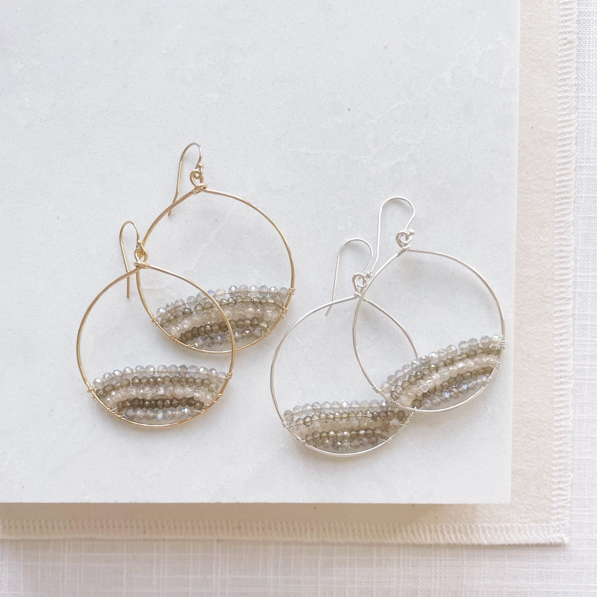 2 pairs of gold and silver gemstone statement 2 inch hoop earrings with rows of zircon, labradorite, and smokey topaz gemstones. Harper Earrings by Sarah Cornwell Jewelry