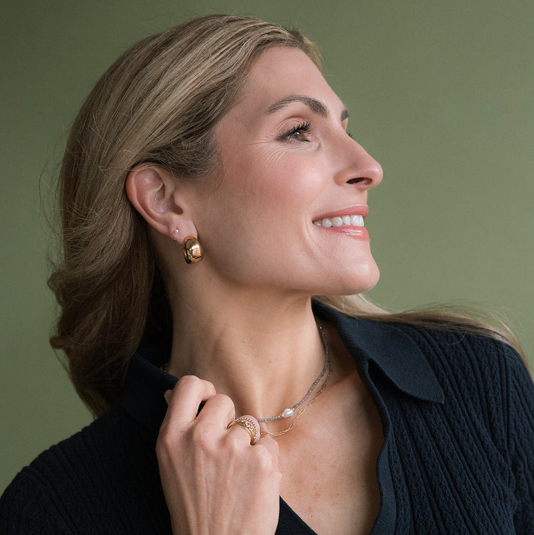 Woman in a navy blue sweater with a chunky gold hoop earring