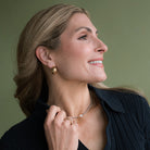 Woman in a navy blue sweater with a chunky gold hoop earring