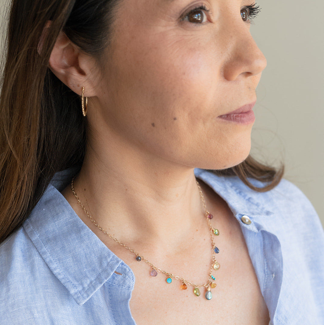 Woman wearing a colorful gemstone necklace with a neutral background