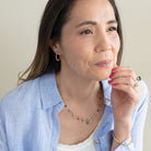 Woman wearing a light blue shirt over a white top, sitting against a plain background