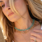 Close-up of a woman wearing gold and turquoise necklaces.